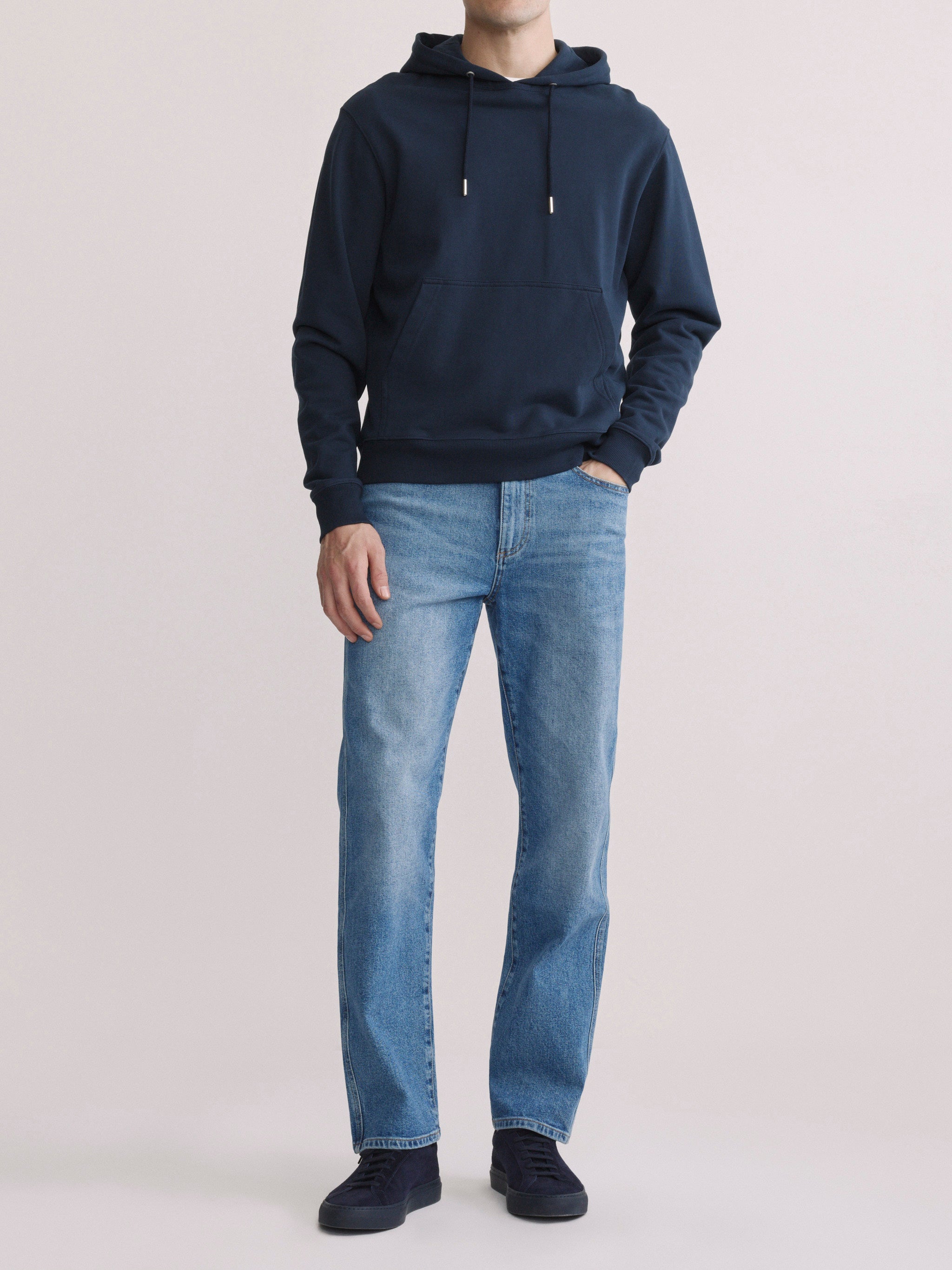 DL1961 men's Chris modern straight jeans in light blue 'Stonecut', front full-length with navy hoodie.