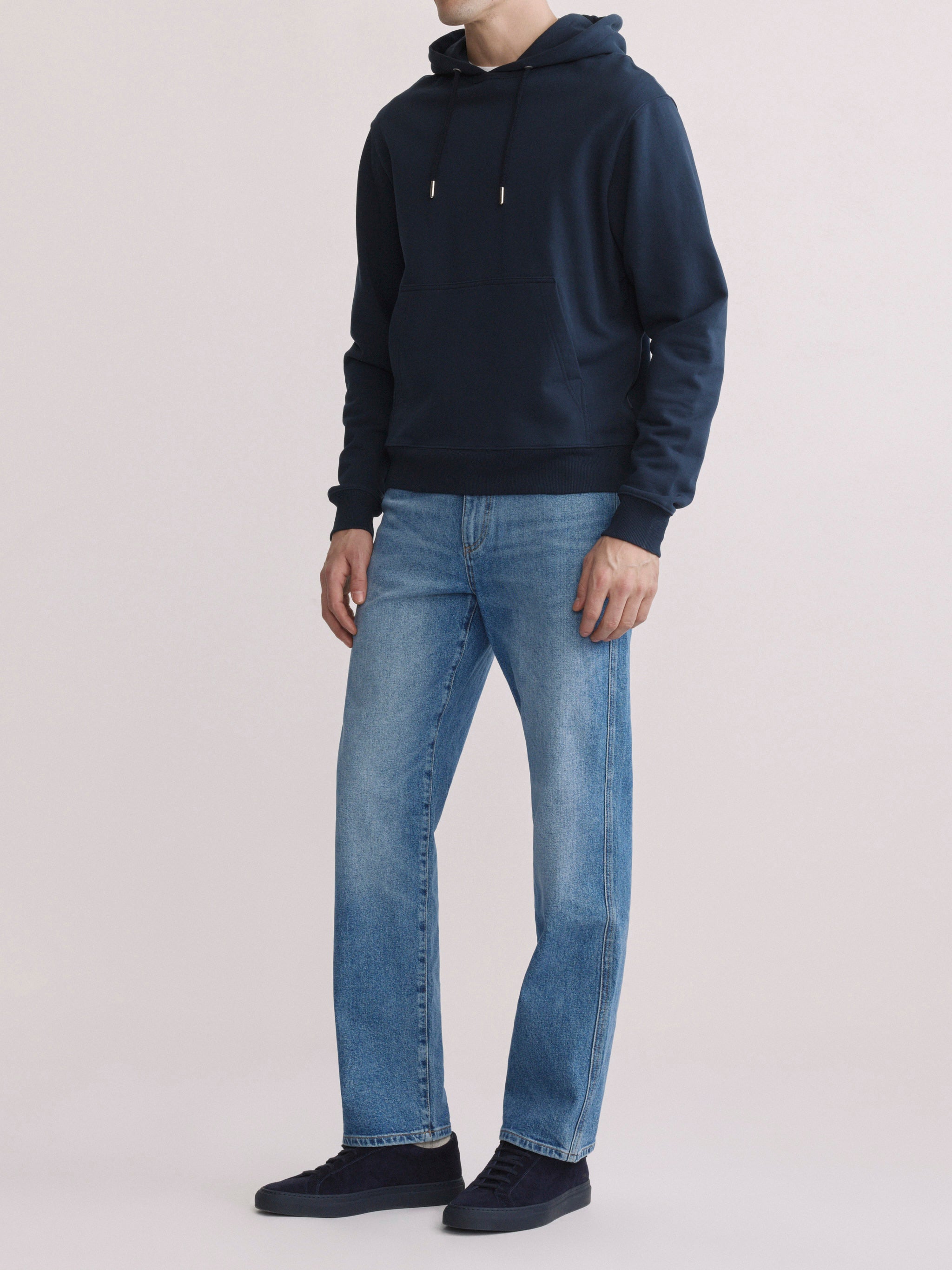 DL1961 men's Chris modern straight jeans in light blue 'Stonecut', three-quarter front view with navy hoodie.
