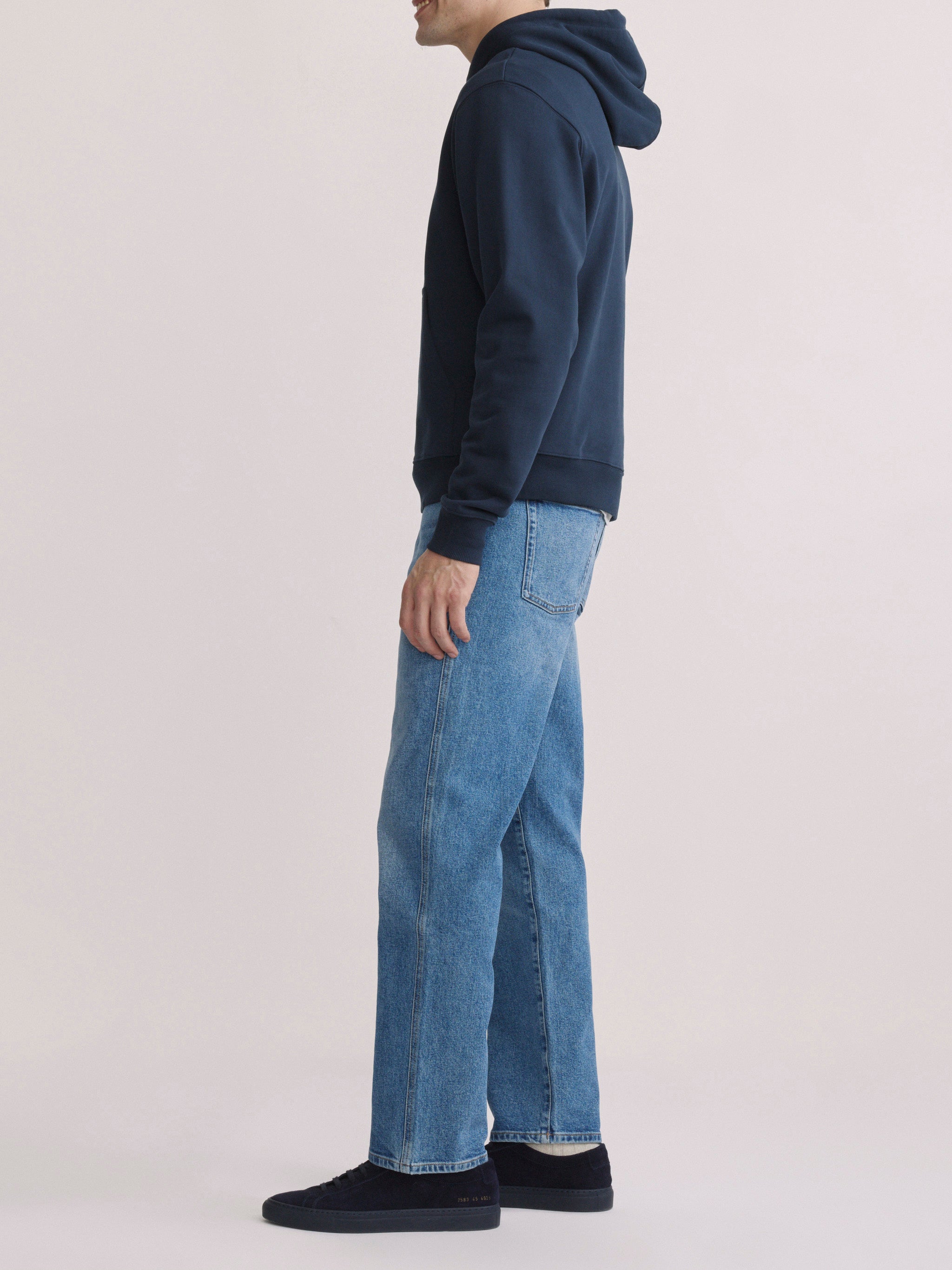 DL1961 men's Chris modern straight jeans in light blue 'Stonecut', full-length side profile with navy hoodie.