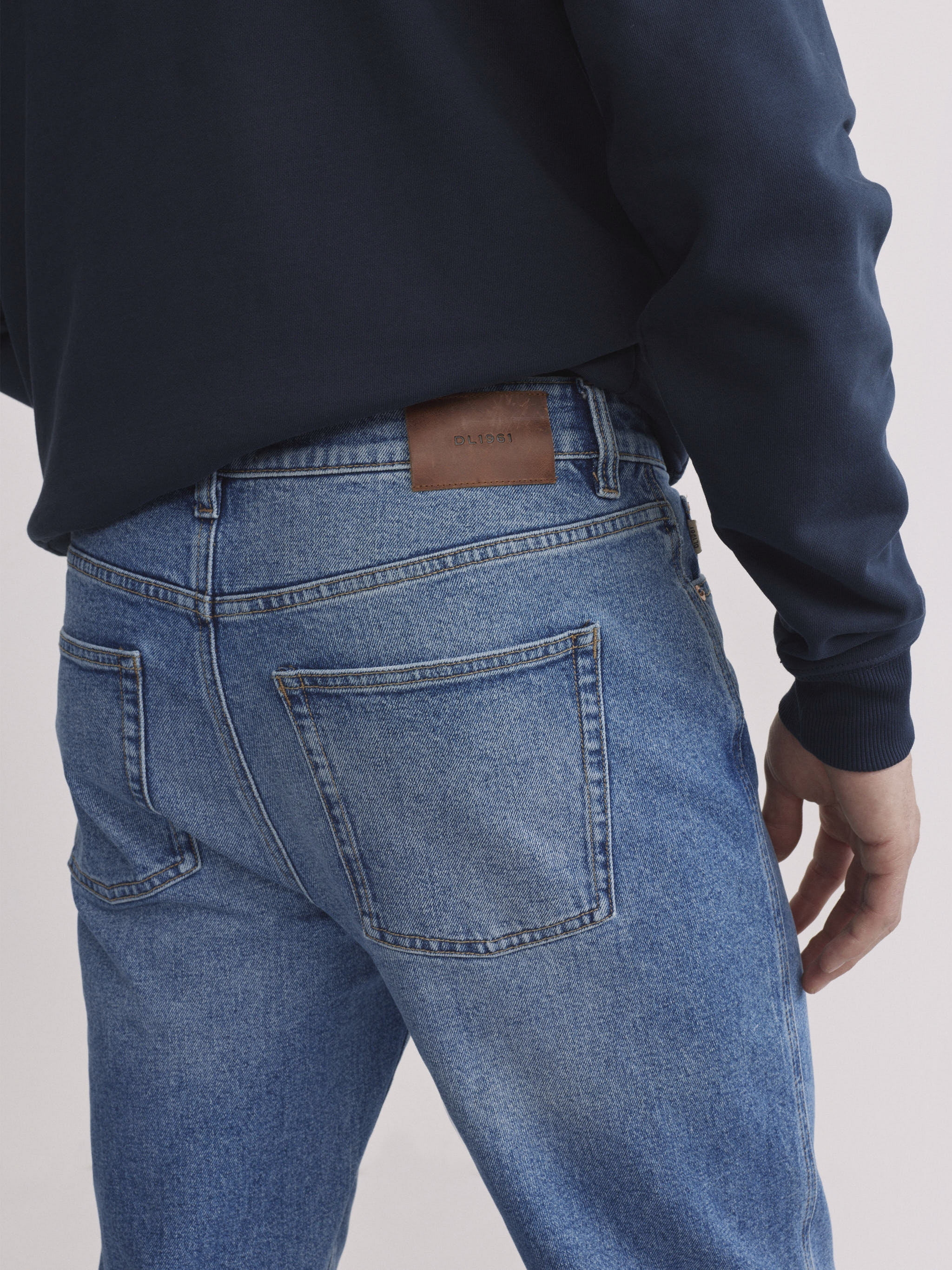 DL1961 men's Chris modern straight jeans in light blue 'Stonecut', close-up of back pocket and leather patch.