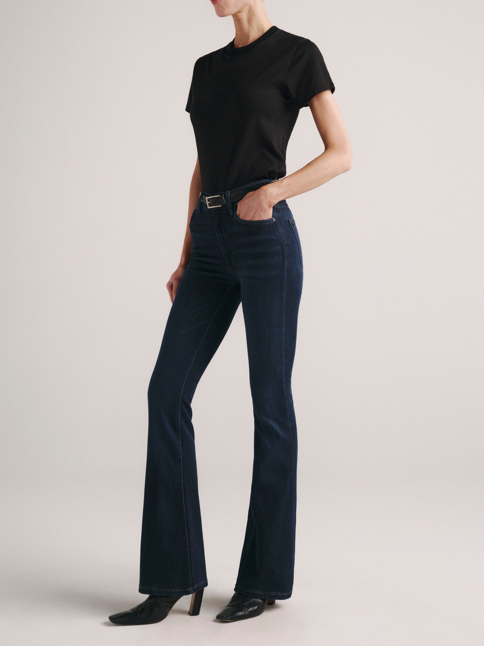 Bridget Boot jeans in Dark Indigo on a model in a black tee, full-length three-quarter view in a studio.
