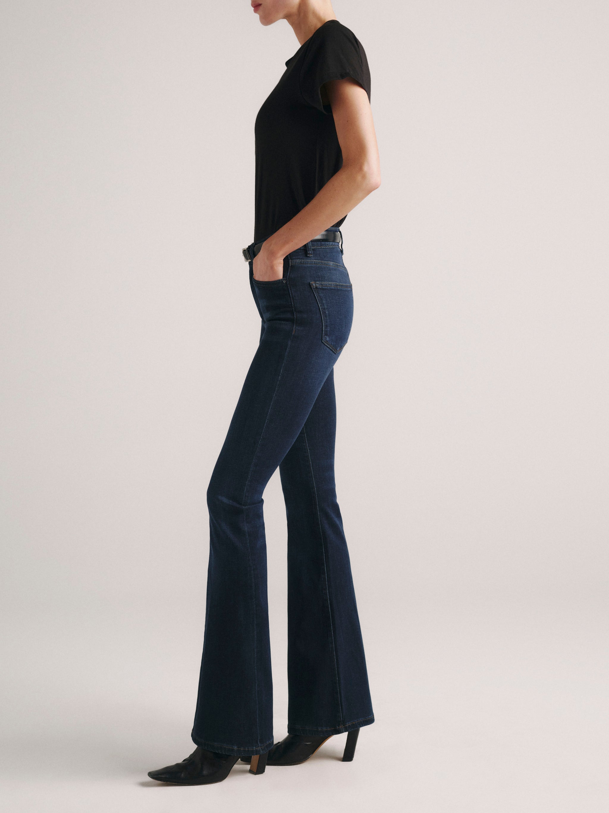 Bridget Boot jeans in Dark Indigo on a model in a black tee, full-length side profile in a studio.
