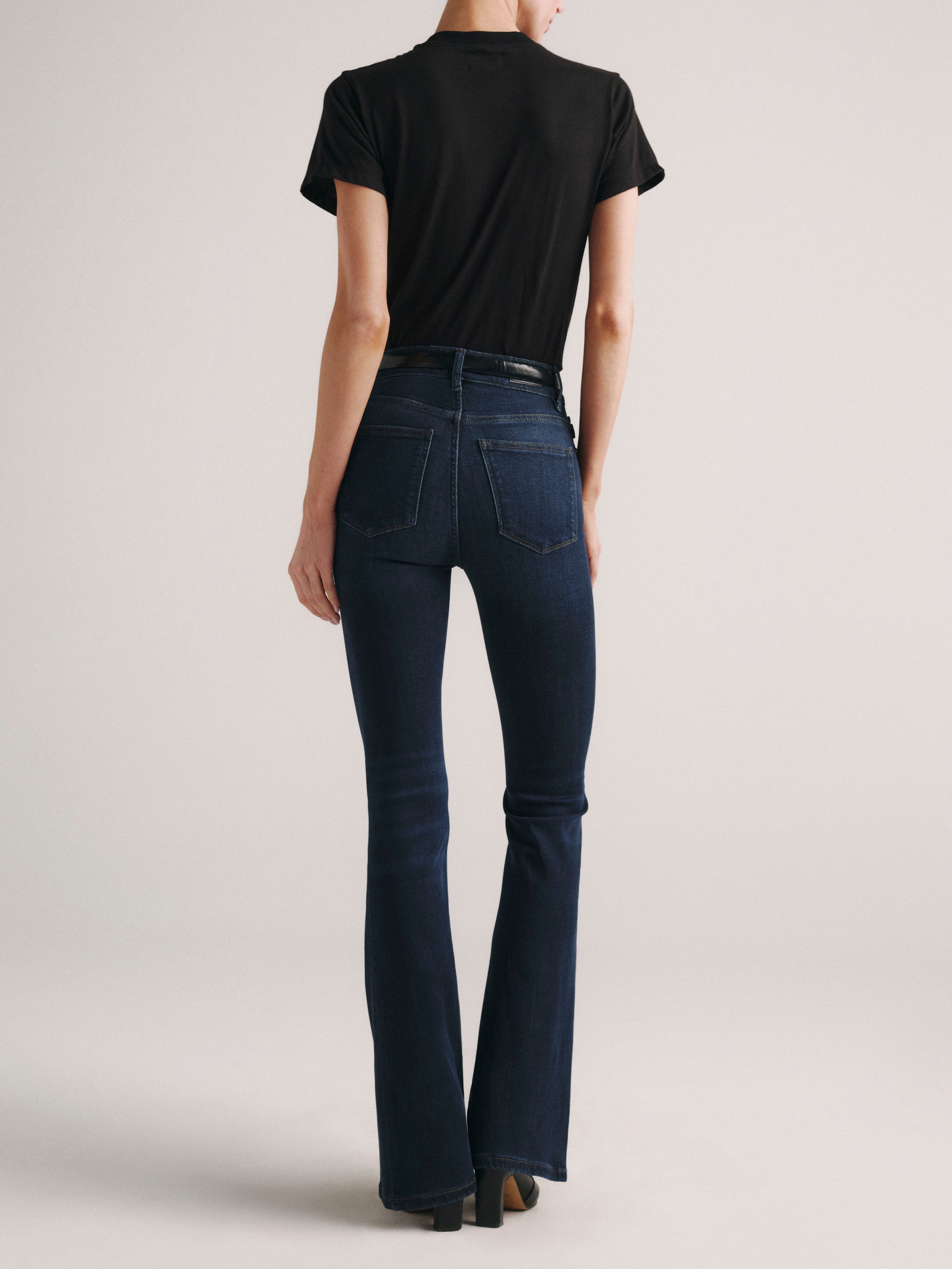 Bridget Boot jeans in Dark Indigo on a model in a black tee, full-length back view in a studio.
