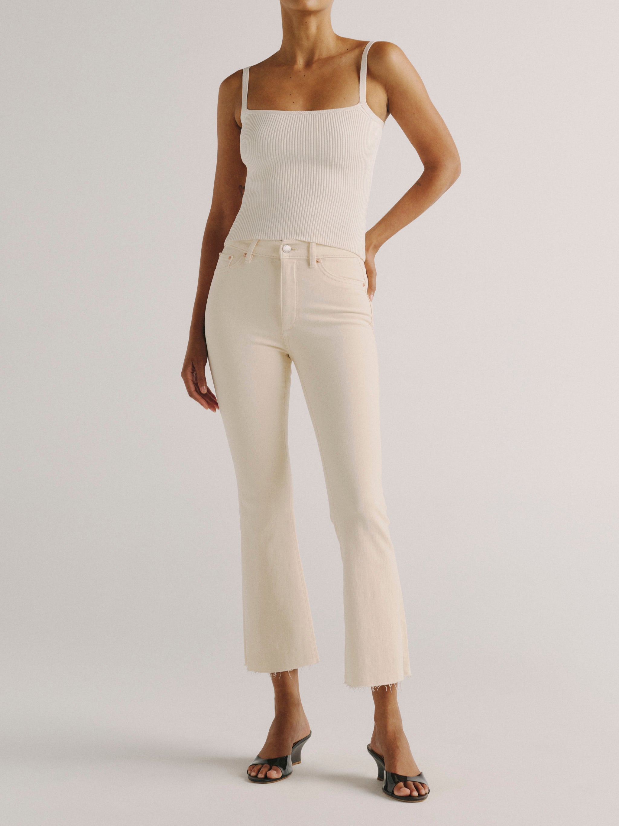 DL1961 women's Bridget Boot High Rise Instasculpt crop jeans in ivory 'Flax', front view styled with a white tank and black sandals.