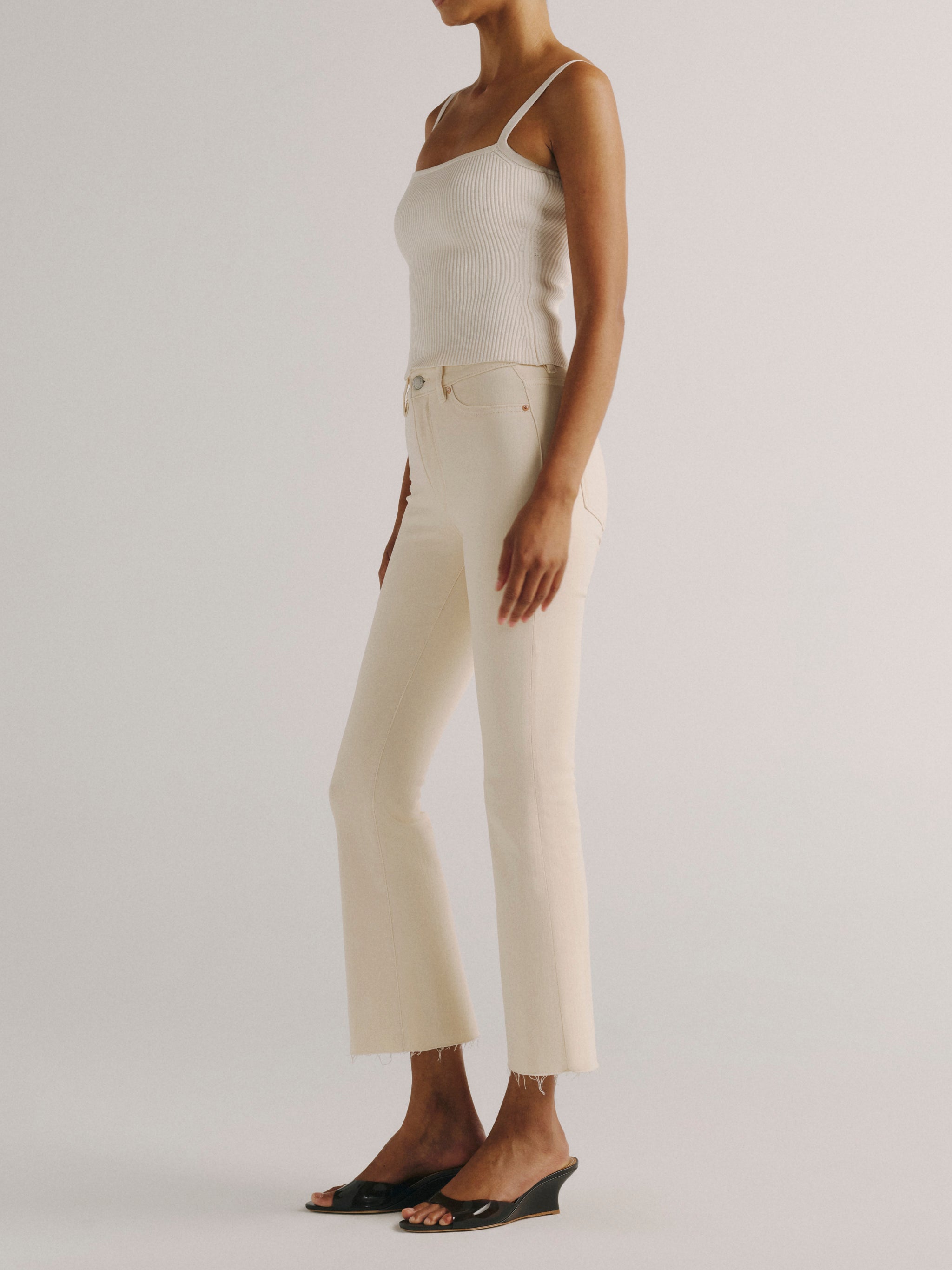 DL1961 women's Bridget Boot High Rise Instasculpt crop jeans in ivory 'Flax', side view showing the cropped flare and raw hem.