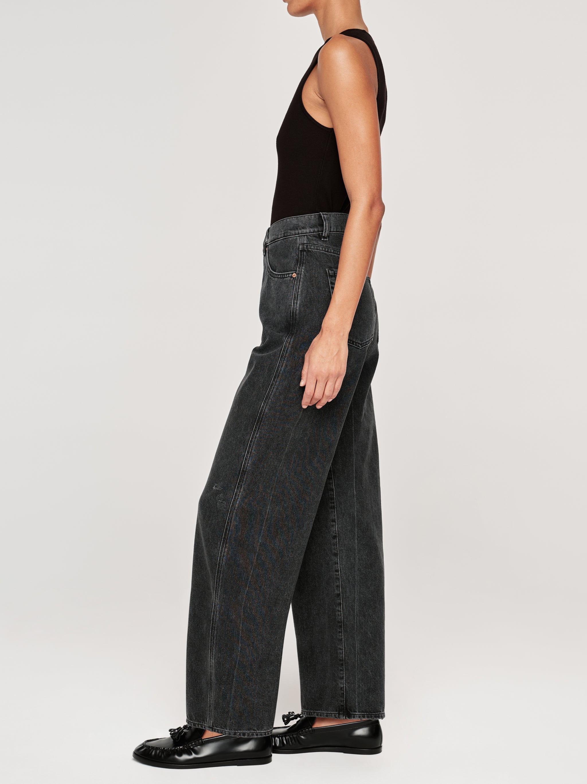 Taylor jeans in Nightshade on a model in a black tank, full-length side profile with black loafers.
