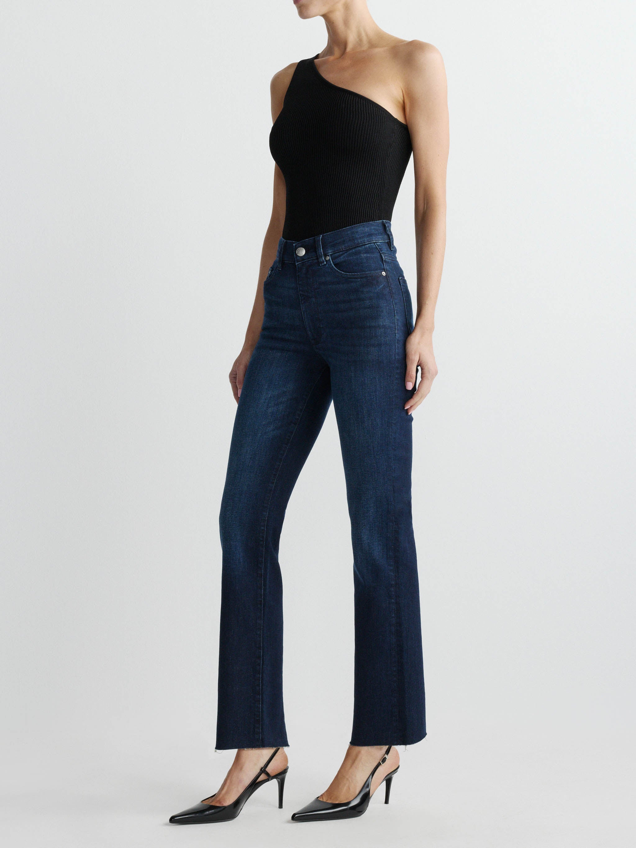 Person wearing dark blue jeans and a black top on a white background