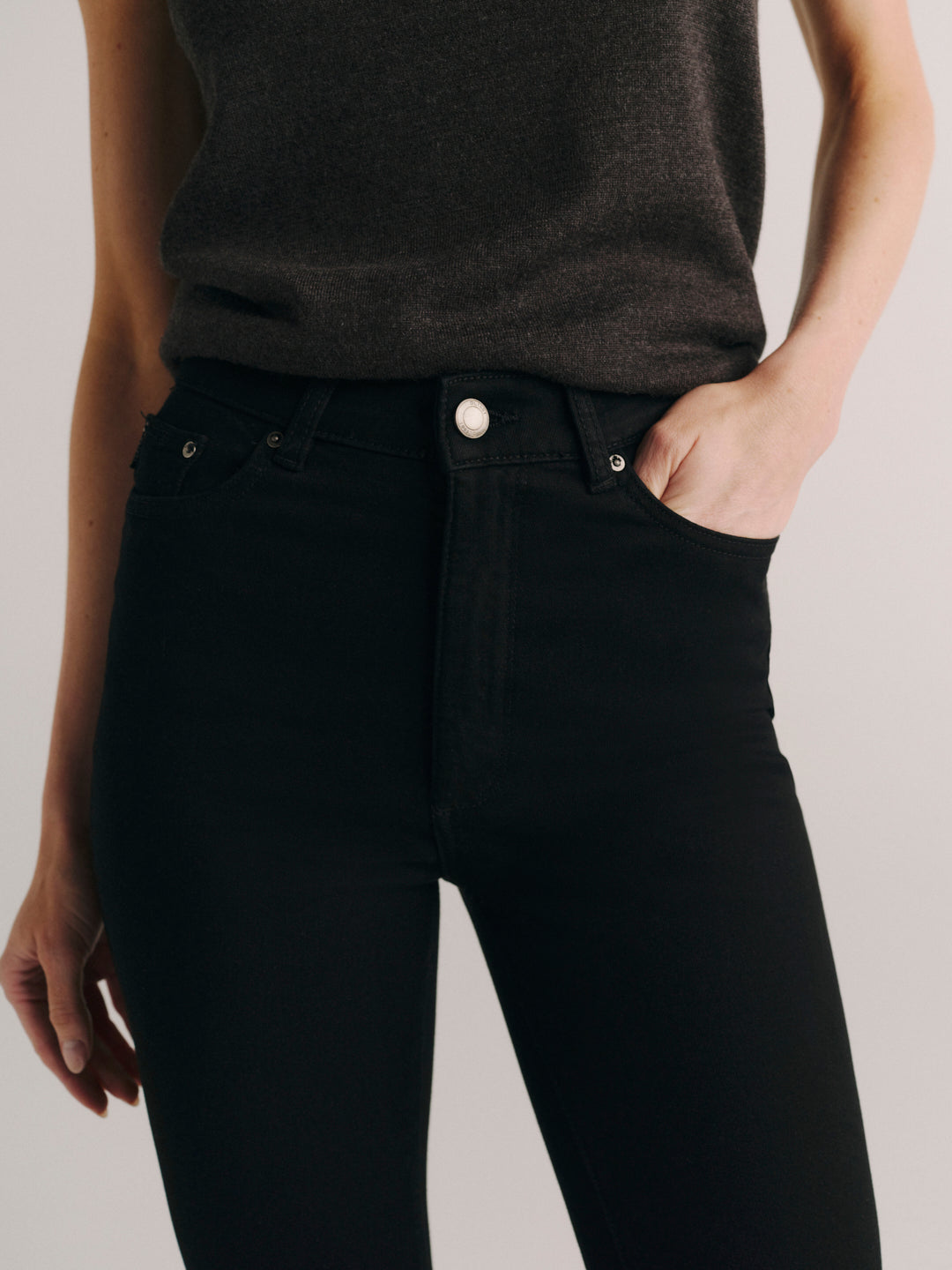 Close-up front detail of DL1961 Halle Straight jeans in black 'Black Peach' wash, high-rise waist, hand in pocket.