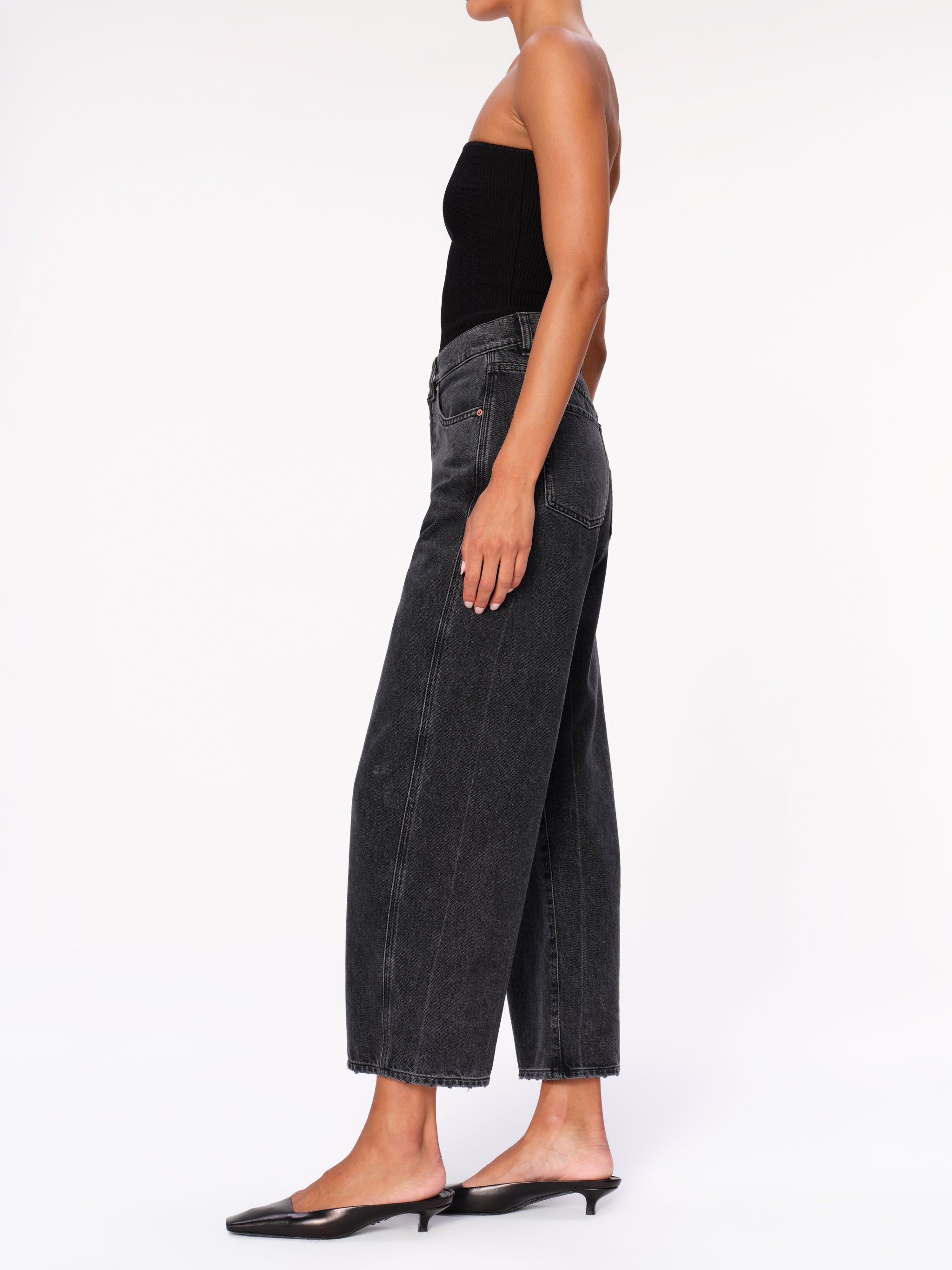 Taylor jeans in Nightshade on a model in a black tube top, full-length side profile in a studio.
