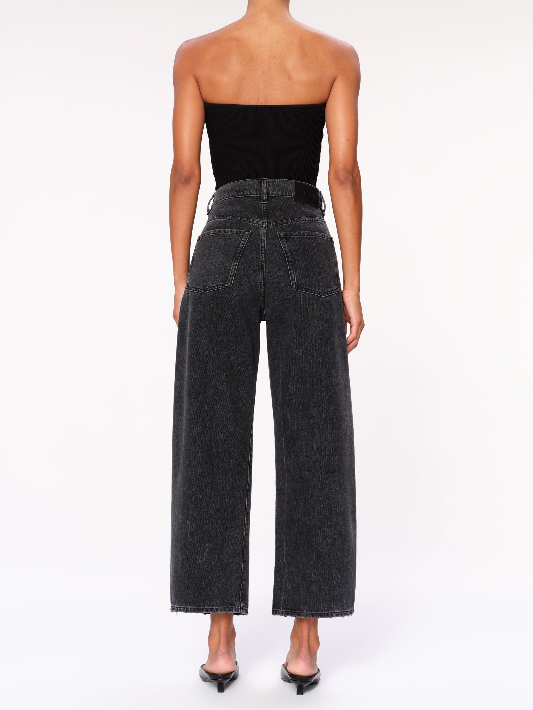 Taylor jeans in Nightshade on a model in a black tube top, full-length back view in a studio.