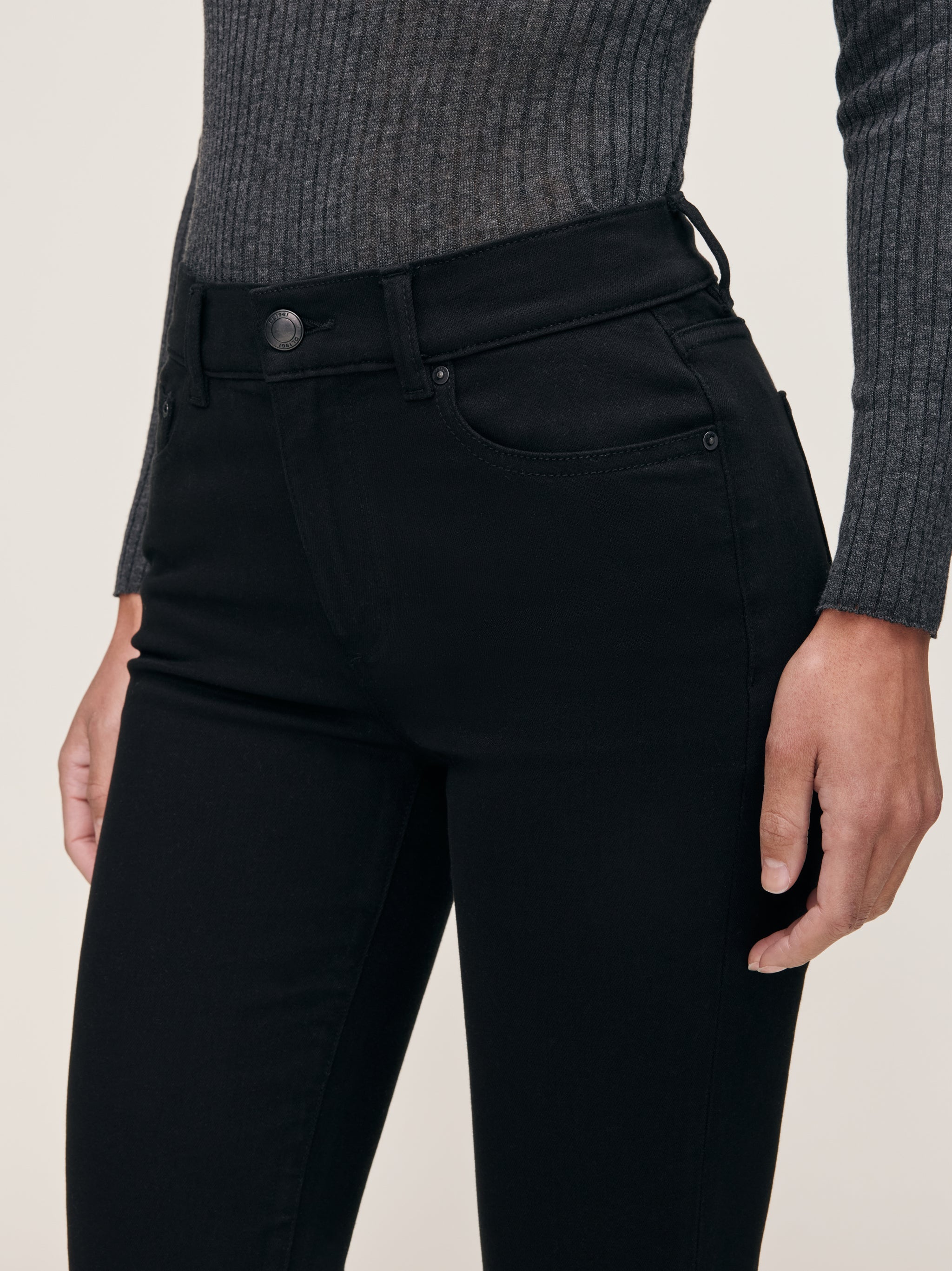 Mara jeans in Black, close-up of the high-rise waist and front pocket on a model.