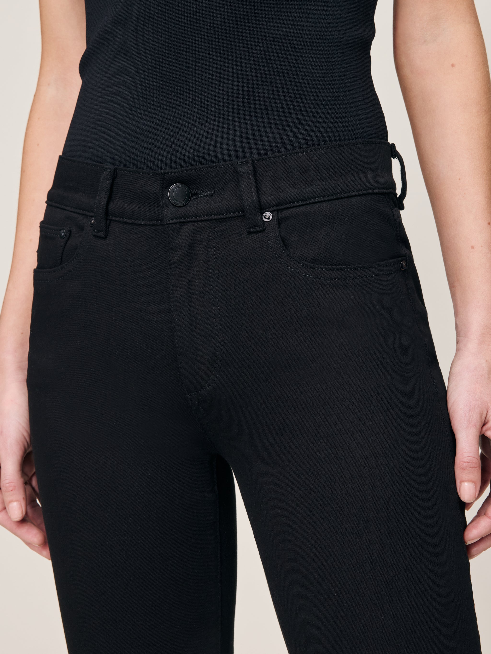 Mara jeans in Black, close-up of the high-rise waist and front pocket on a model.