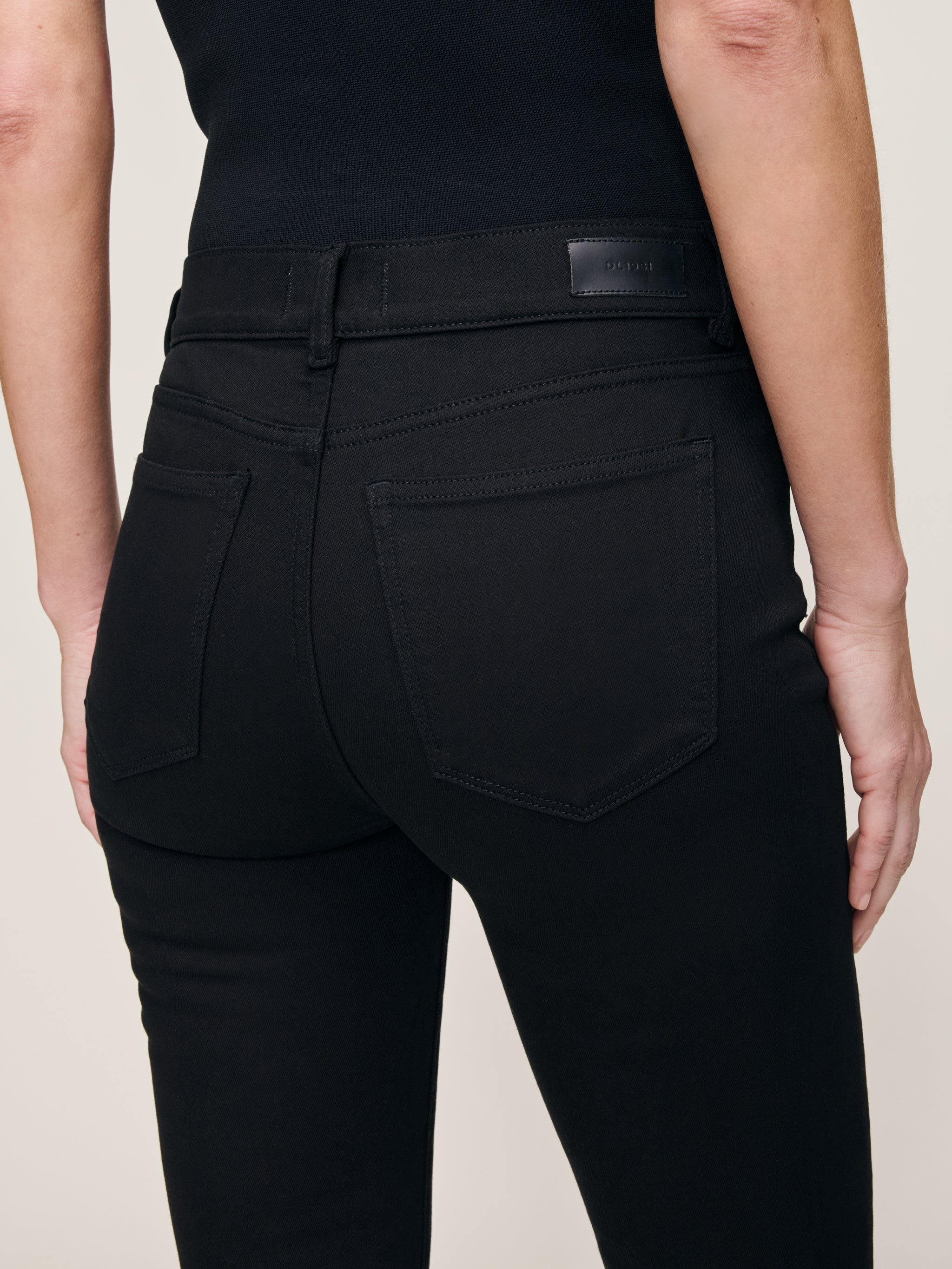 Mara jeans in Black, close-up of the high-rise waist and back pocket on a model.