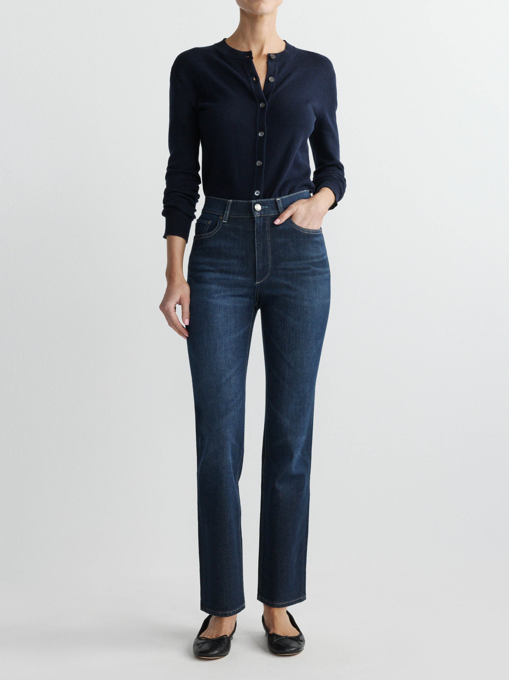 Person wearing a navy button-up shirt and dark blue jeans on a white background