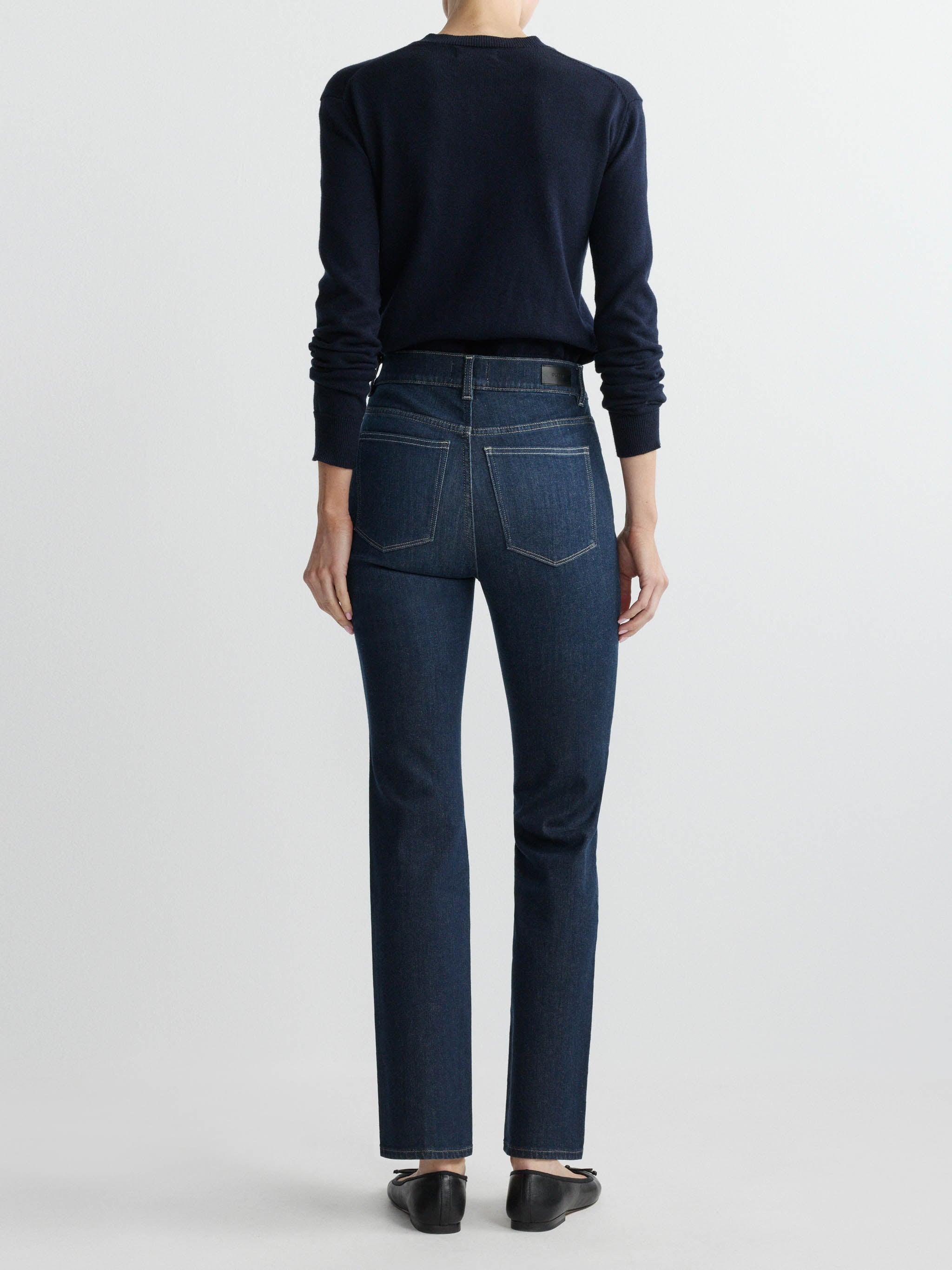 Person wearing dark blue jeans and a matching top on a white background