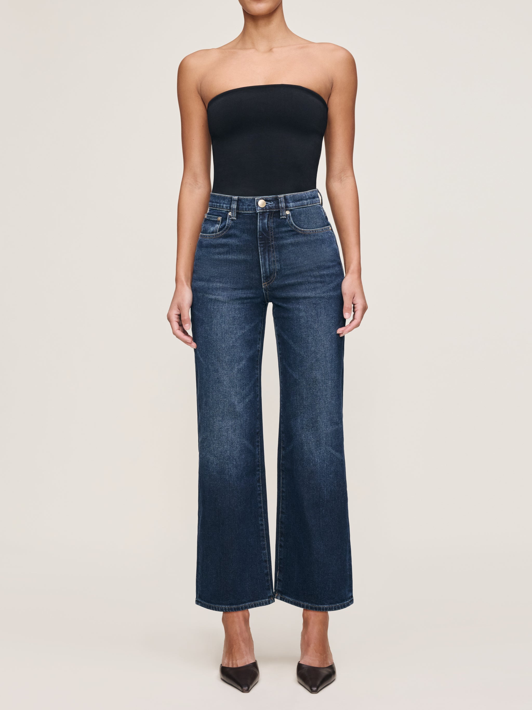 Karmine jeans in Dark Sea on a model in a black tube top, full-length front view with pointed heels.