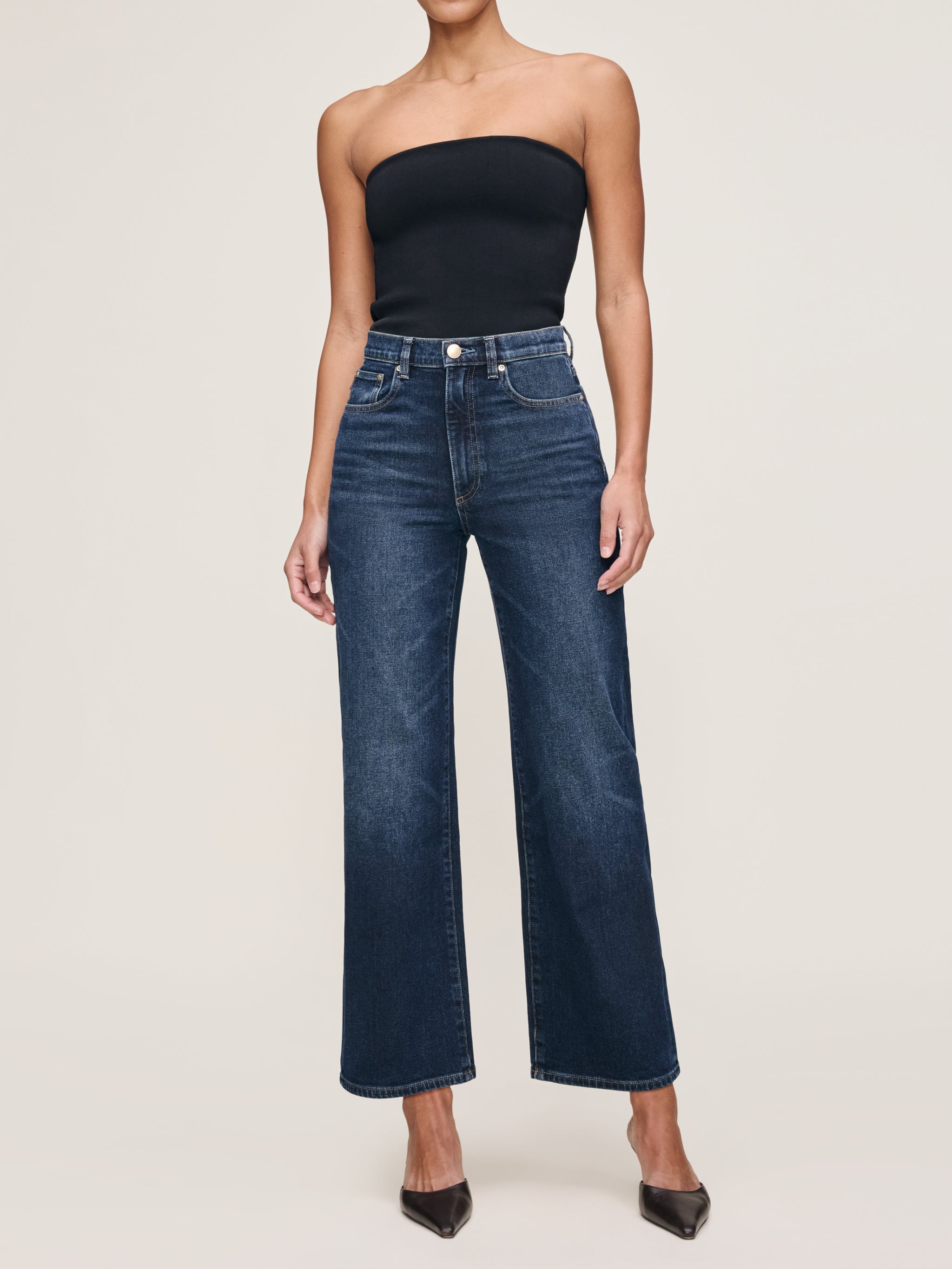 Karmine jeans in Dark Sea on a model in a black tube top, full-length front view in a studio.
