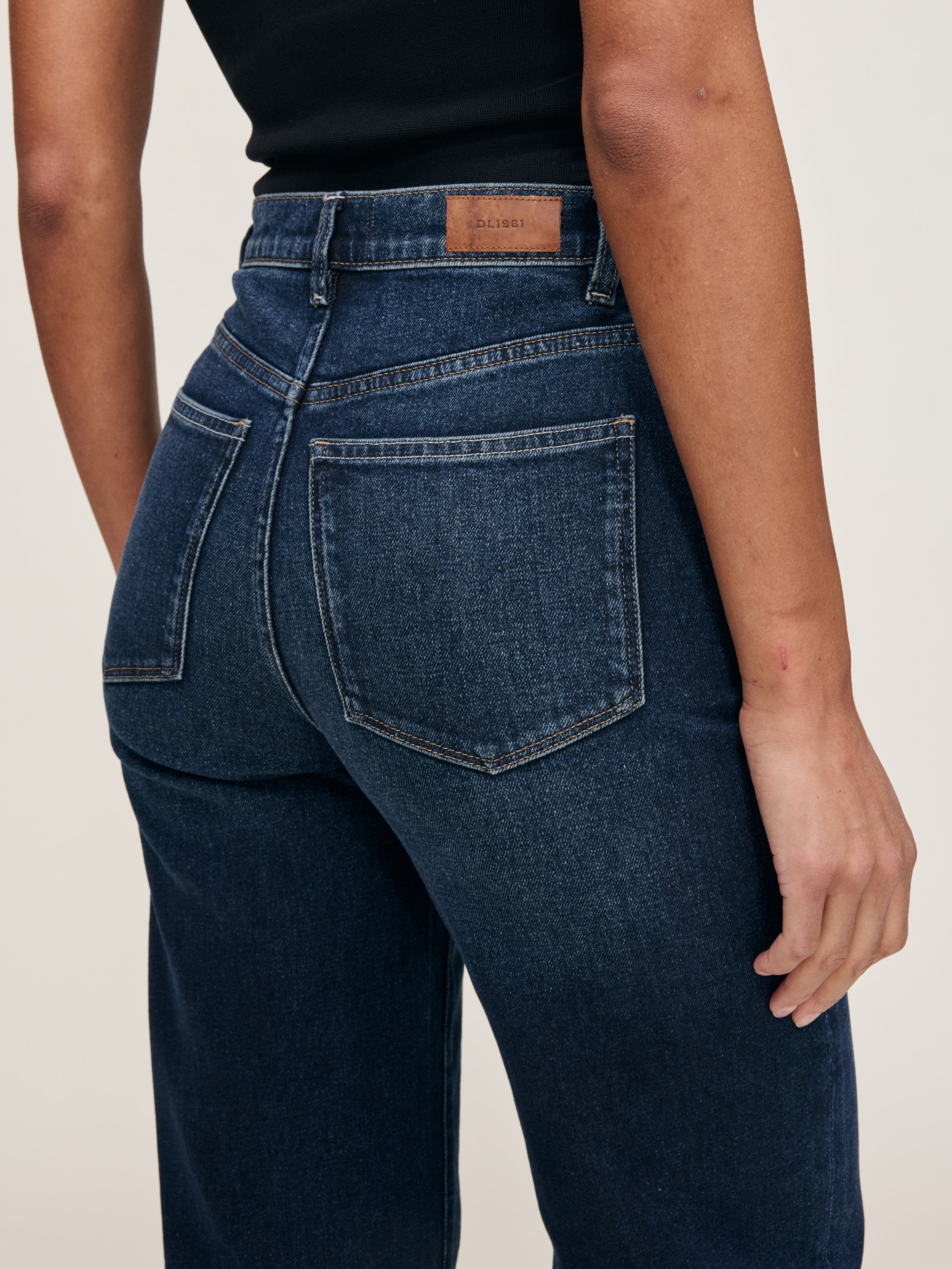 Karmine jeans in Dark Sea on a model, close-up back view of the waist and pocket in a studio.