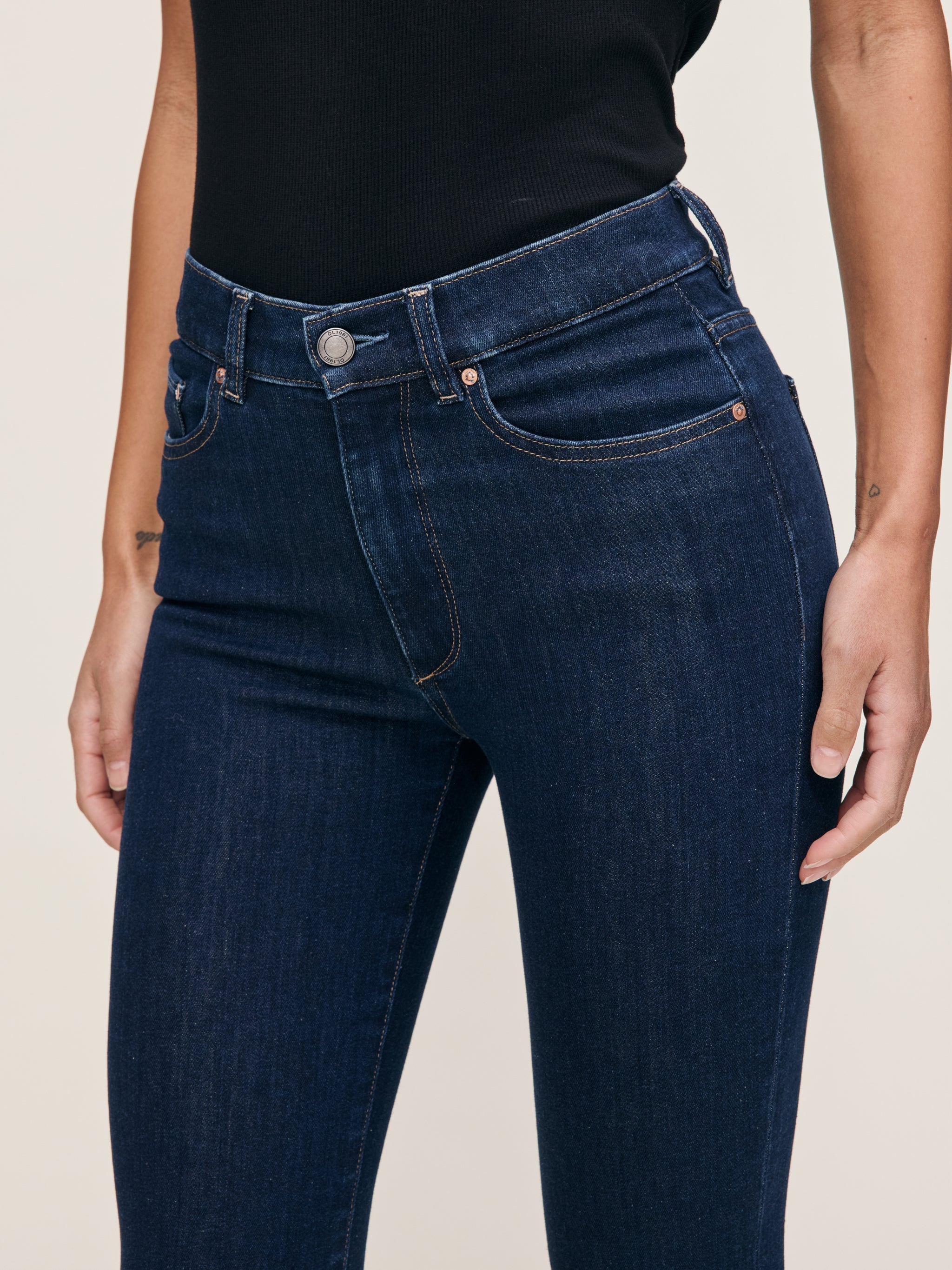 Bridget jeans in Lunar Sky on a model, close-up front view of the waist and pocket in a studio.
