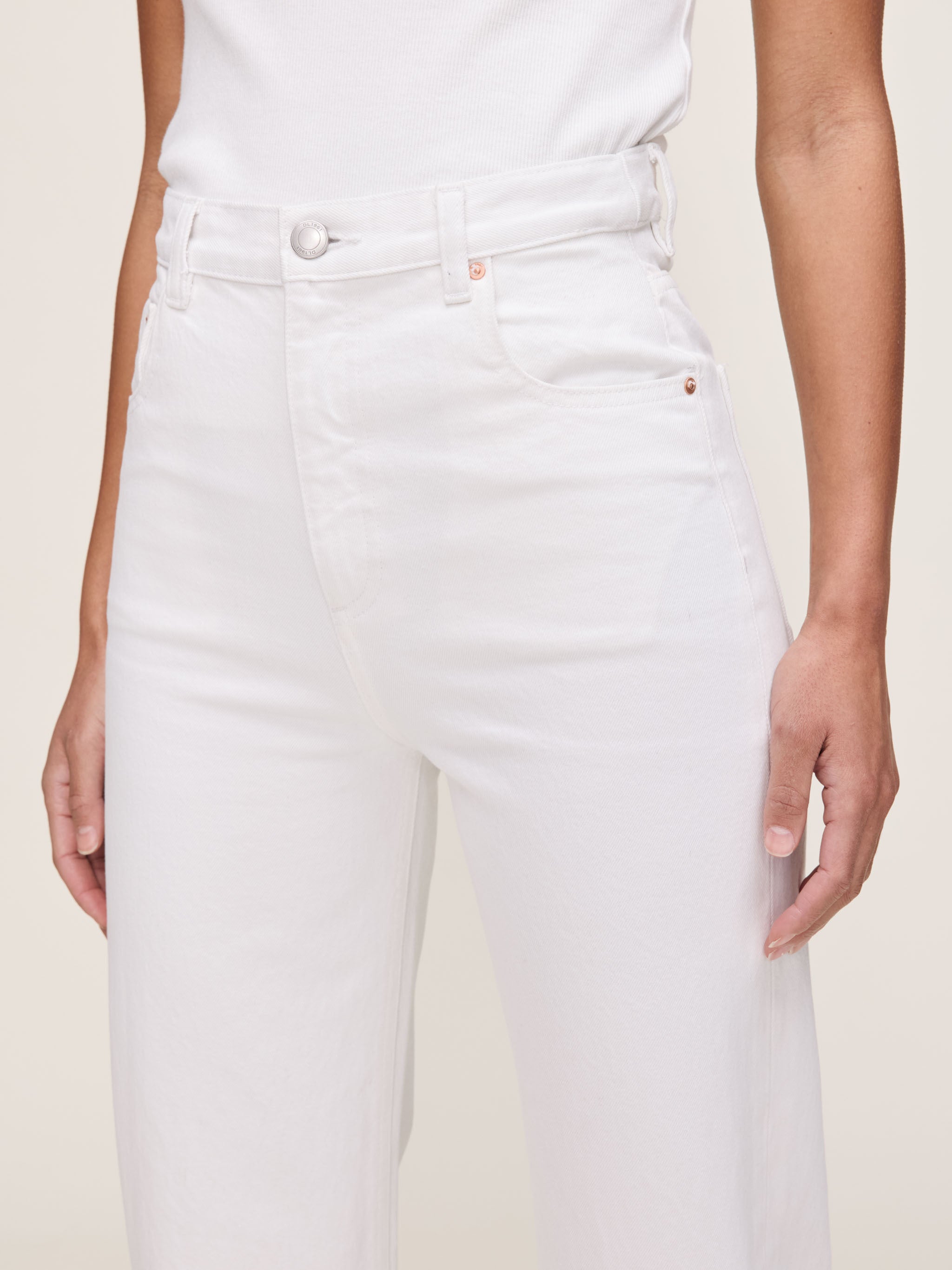 White jeans worn by a person on a plain background