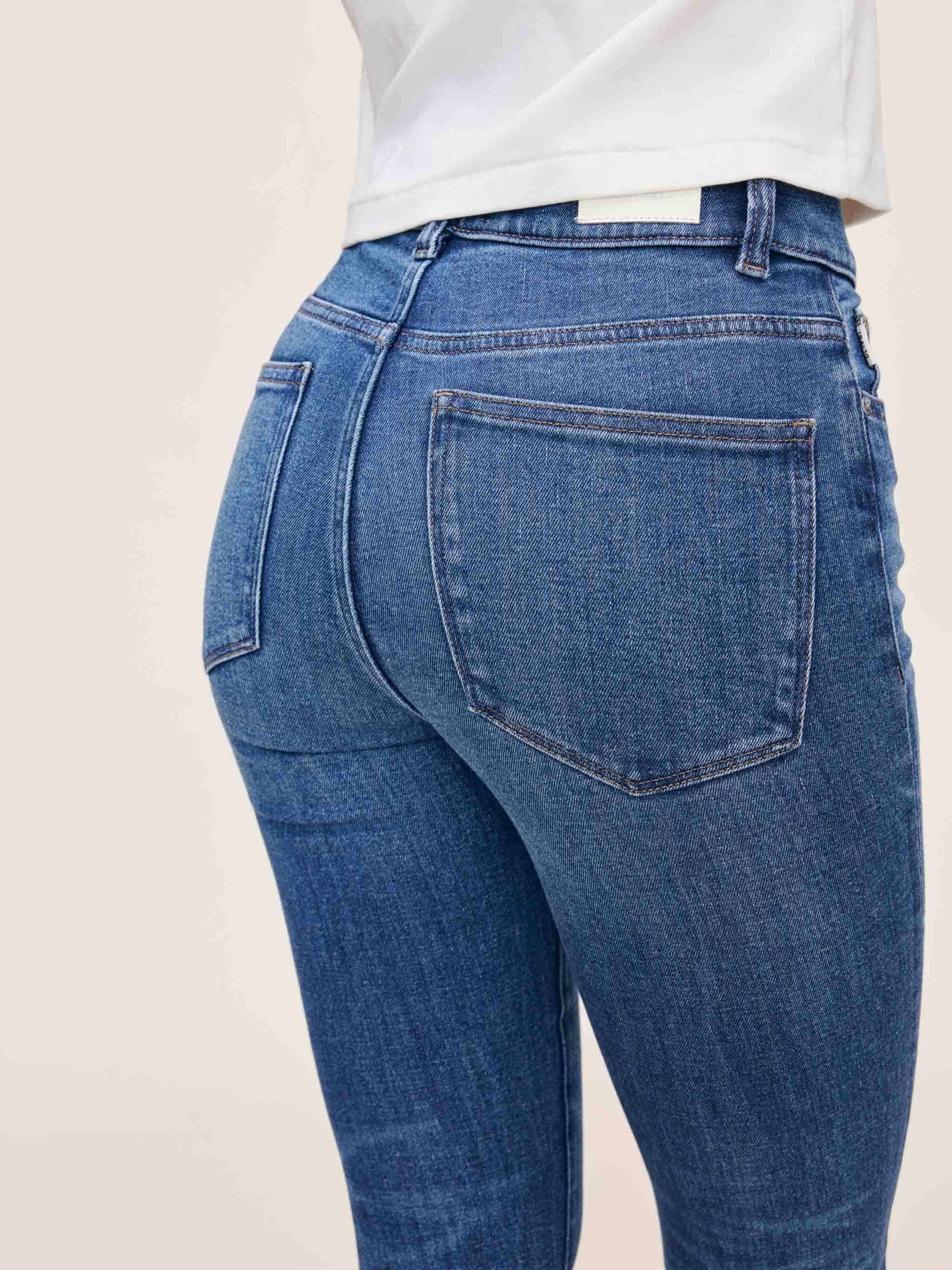 Blue jeans worn by a person on a plain background