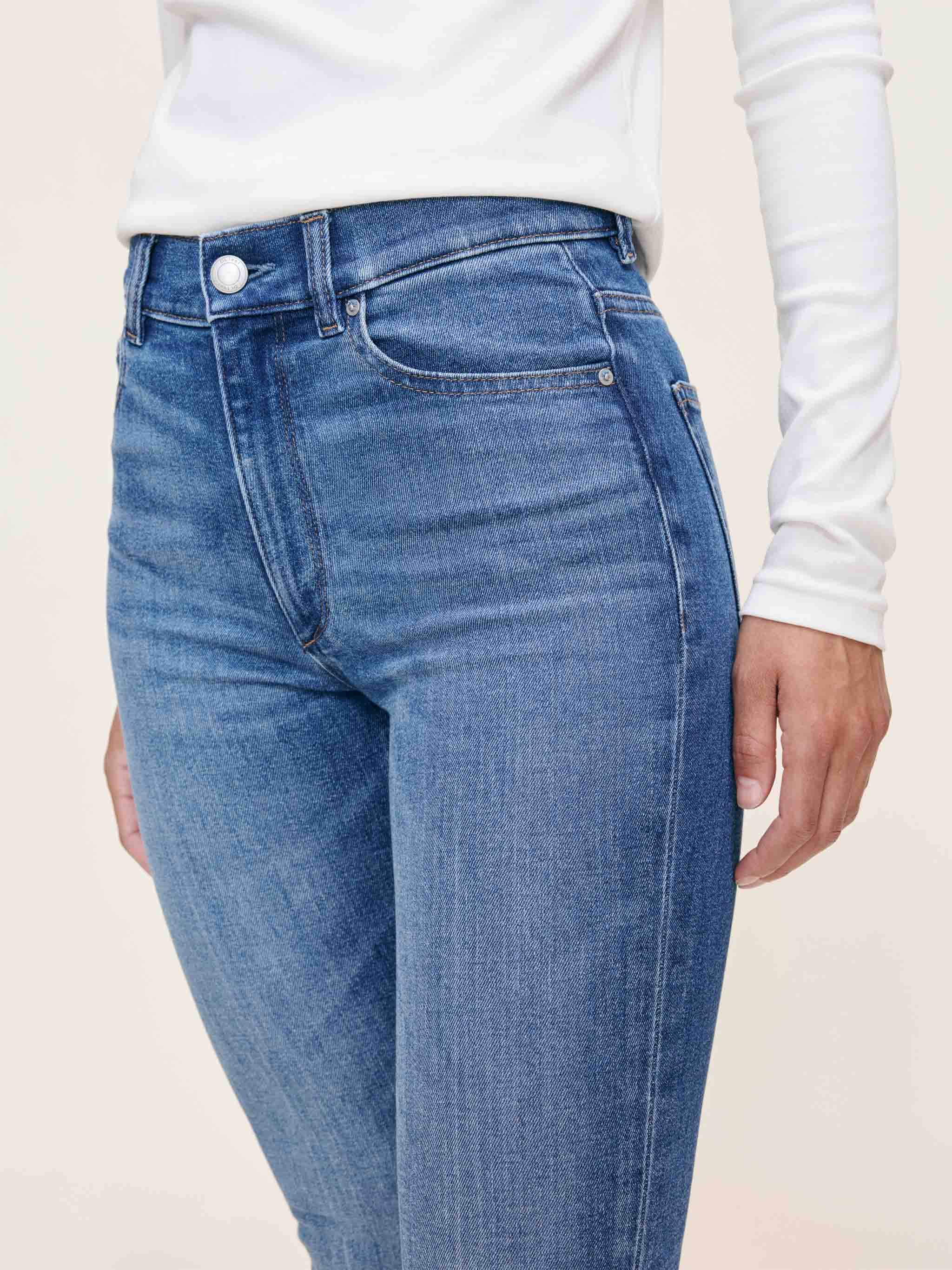 Person wearing blue jeans with a plain background