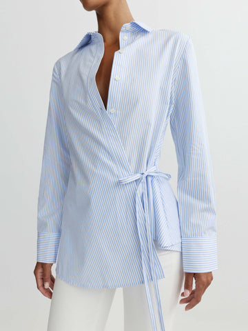 Woman wearing a blue and white striped shirt with a tie waist on a light gray background