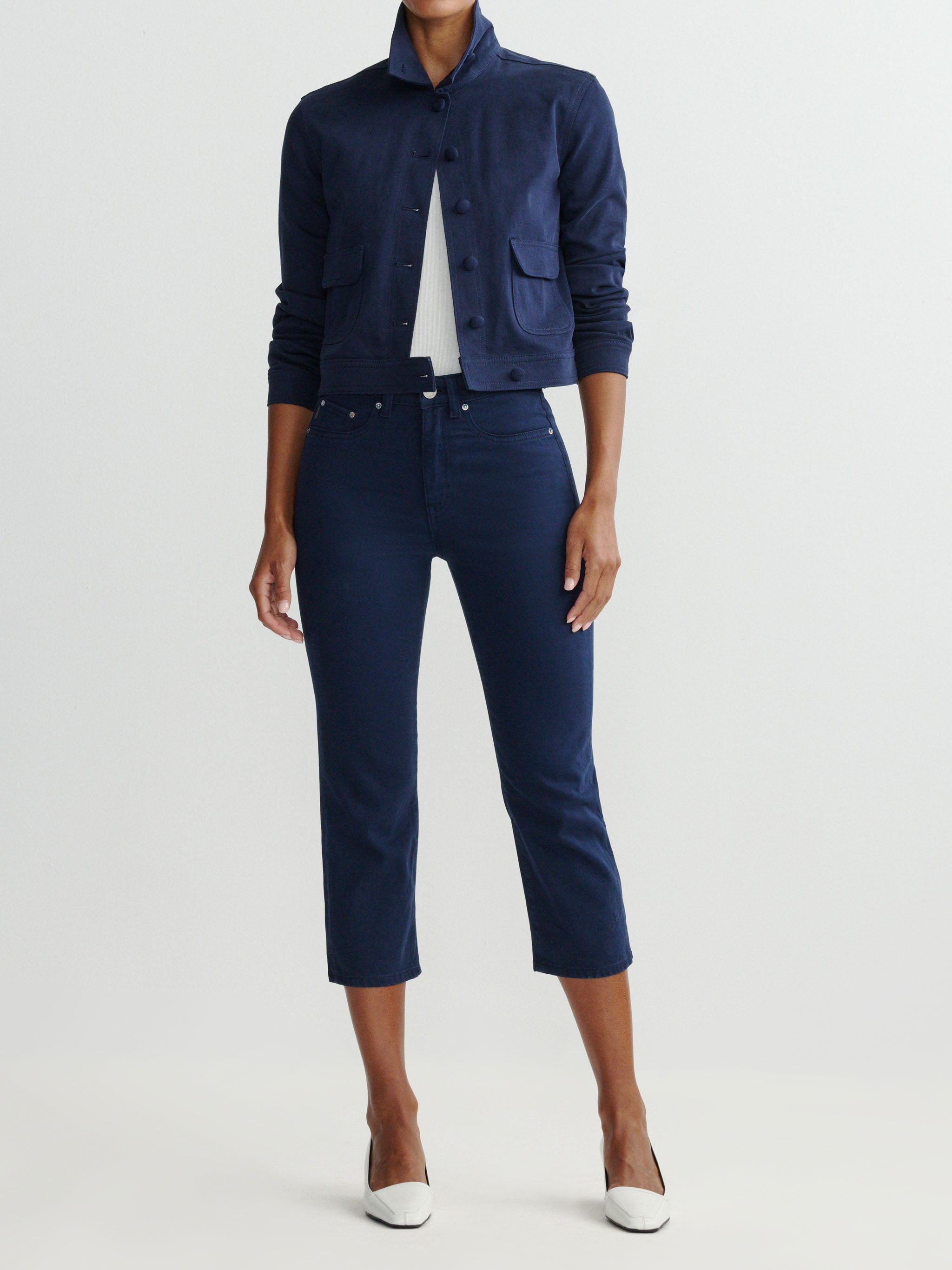 Person wearing a navy jacket and pants on a white background