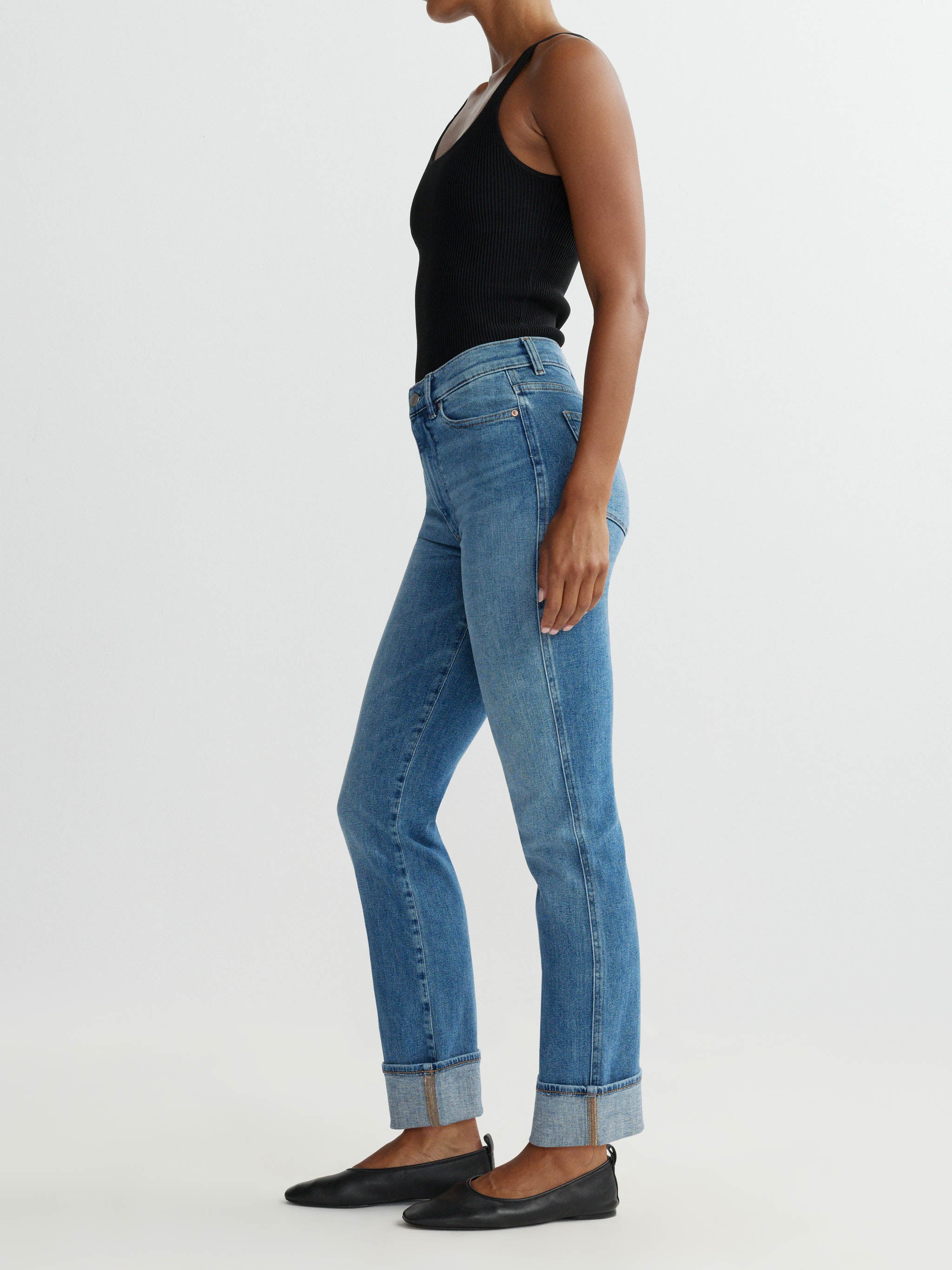 Person wearing blue jeans and a black top on a white background
