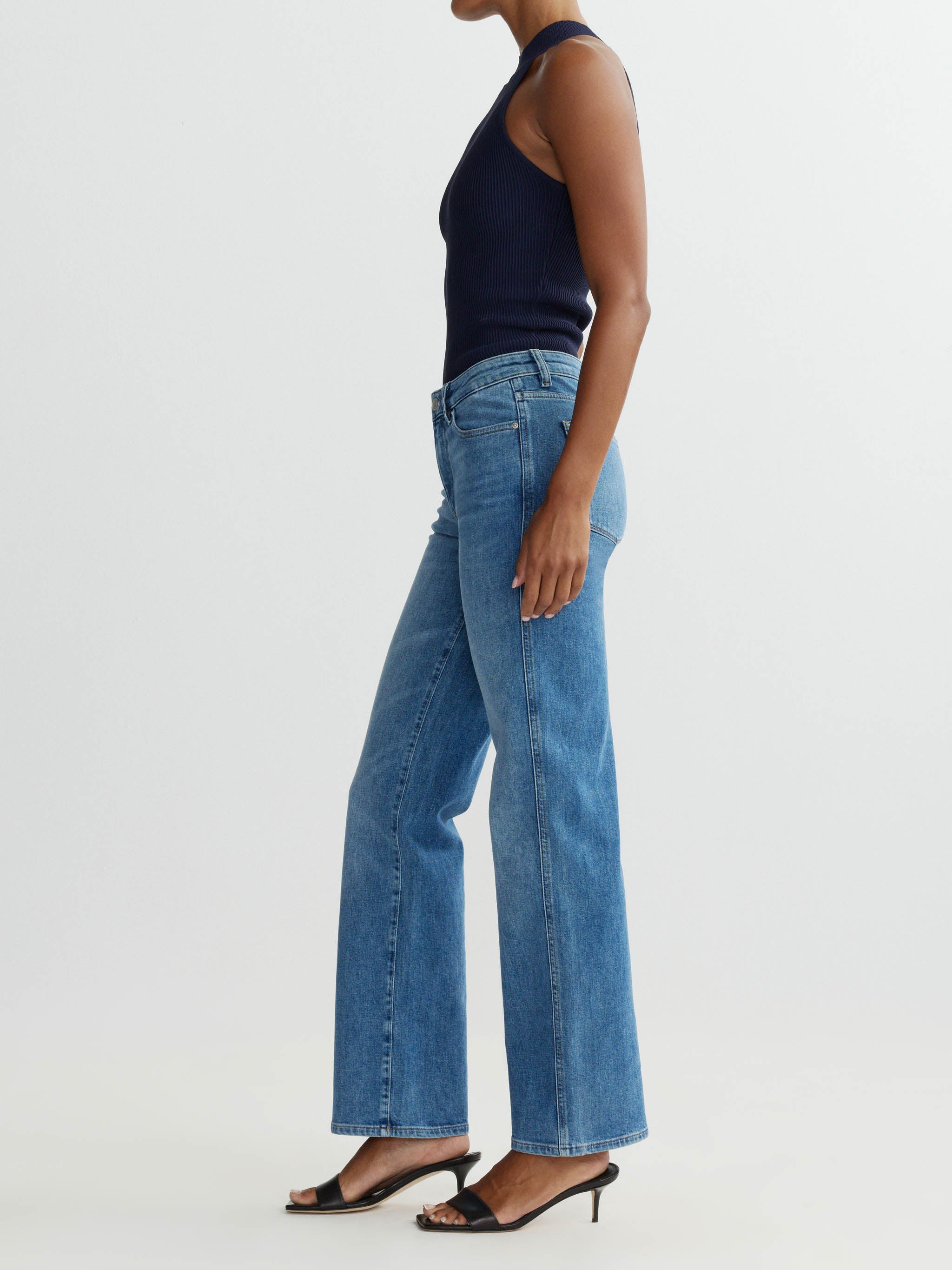Person wearing blue jeans and a dark top on a white background