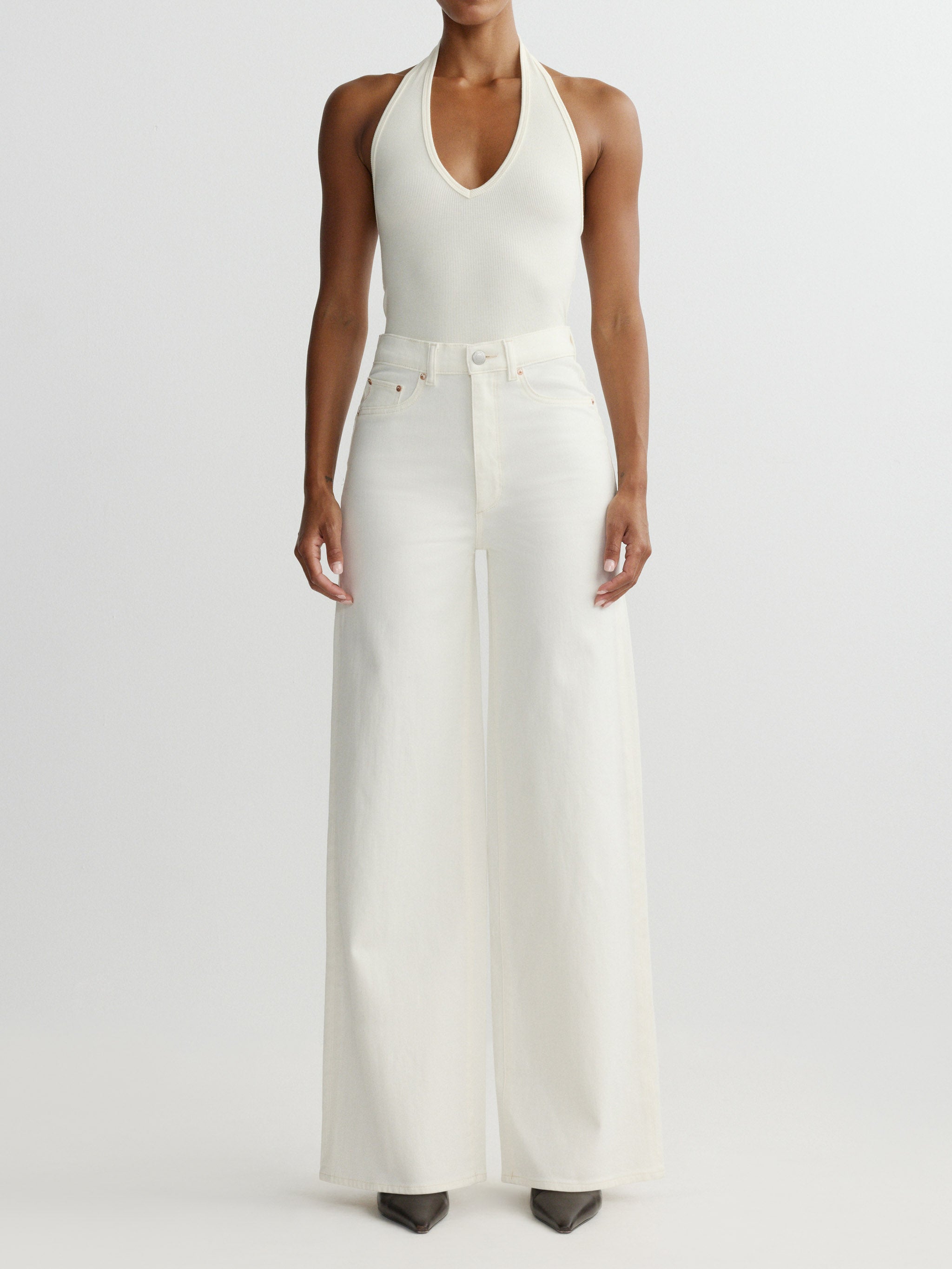 Woman wearing a white halter top and wide-leg pants on a light gray background