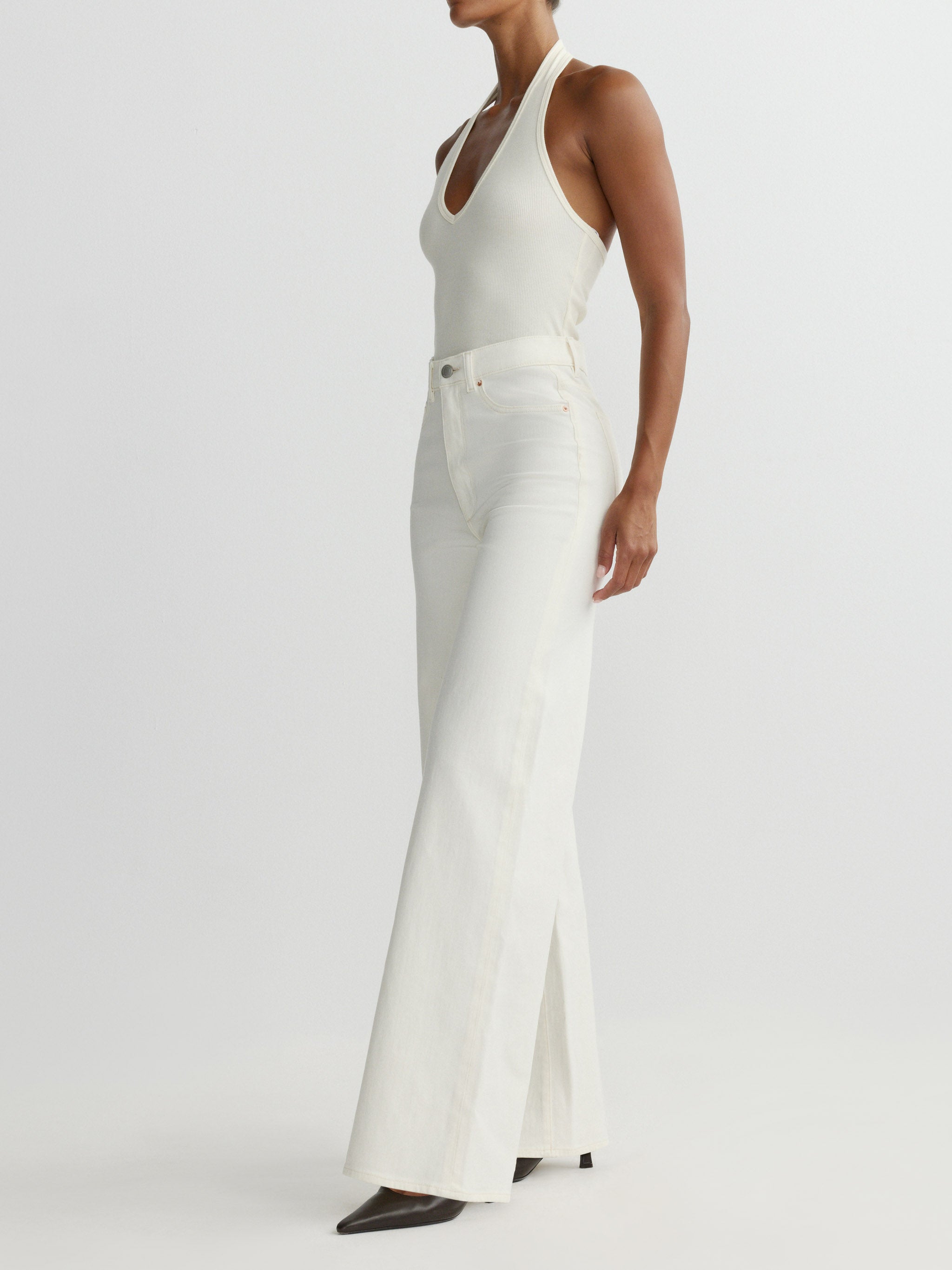 Woman wearing a white sleeveless dress on a plain background