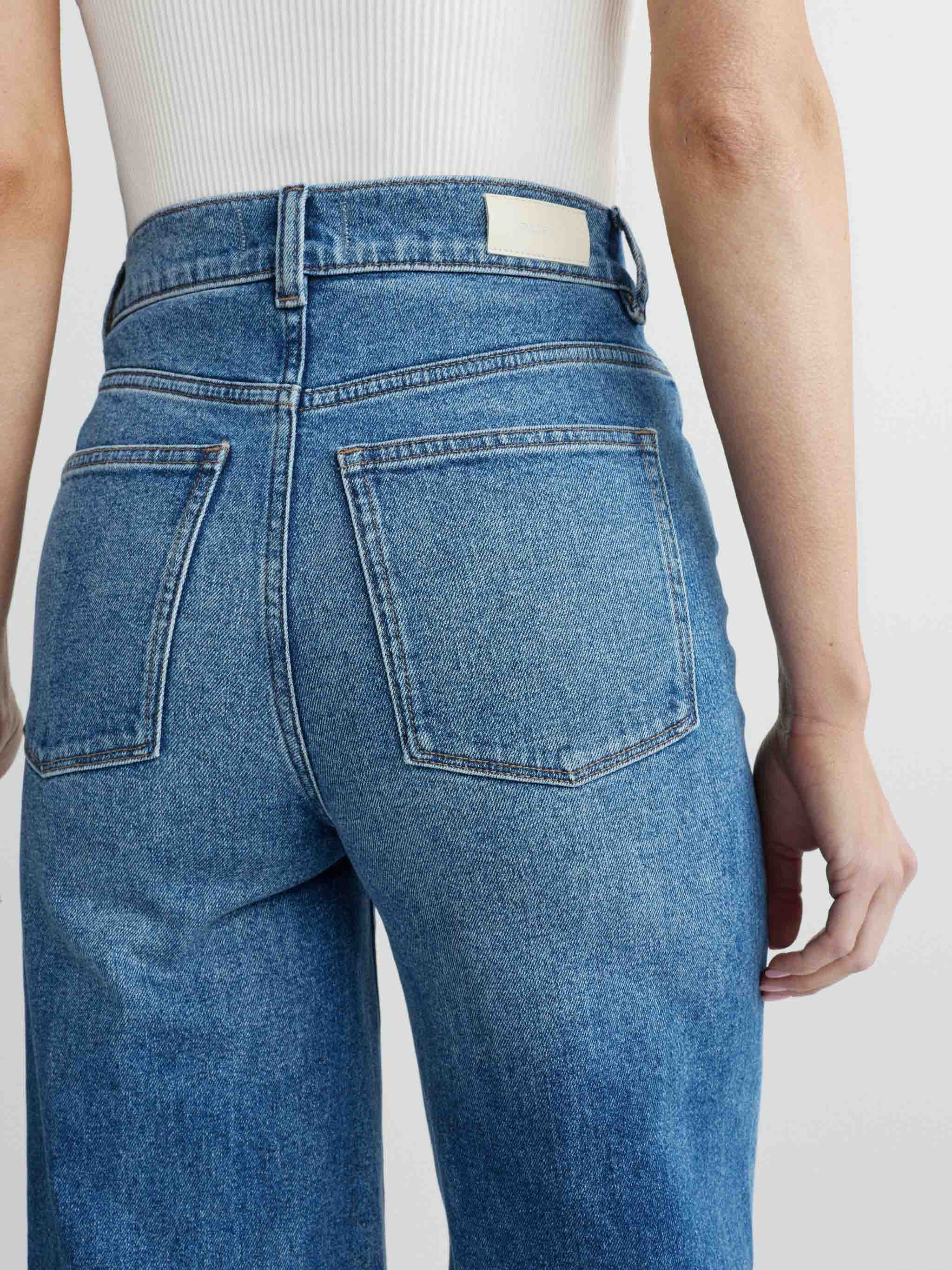 Blue jeans worn by a person on a plain background