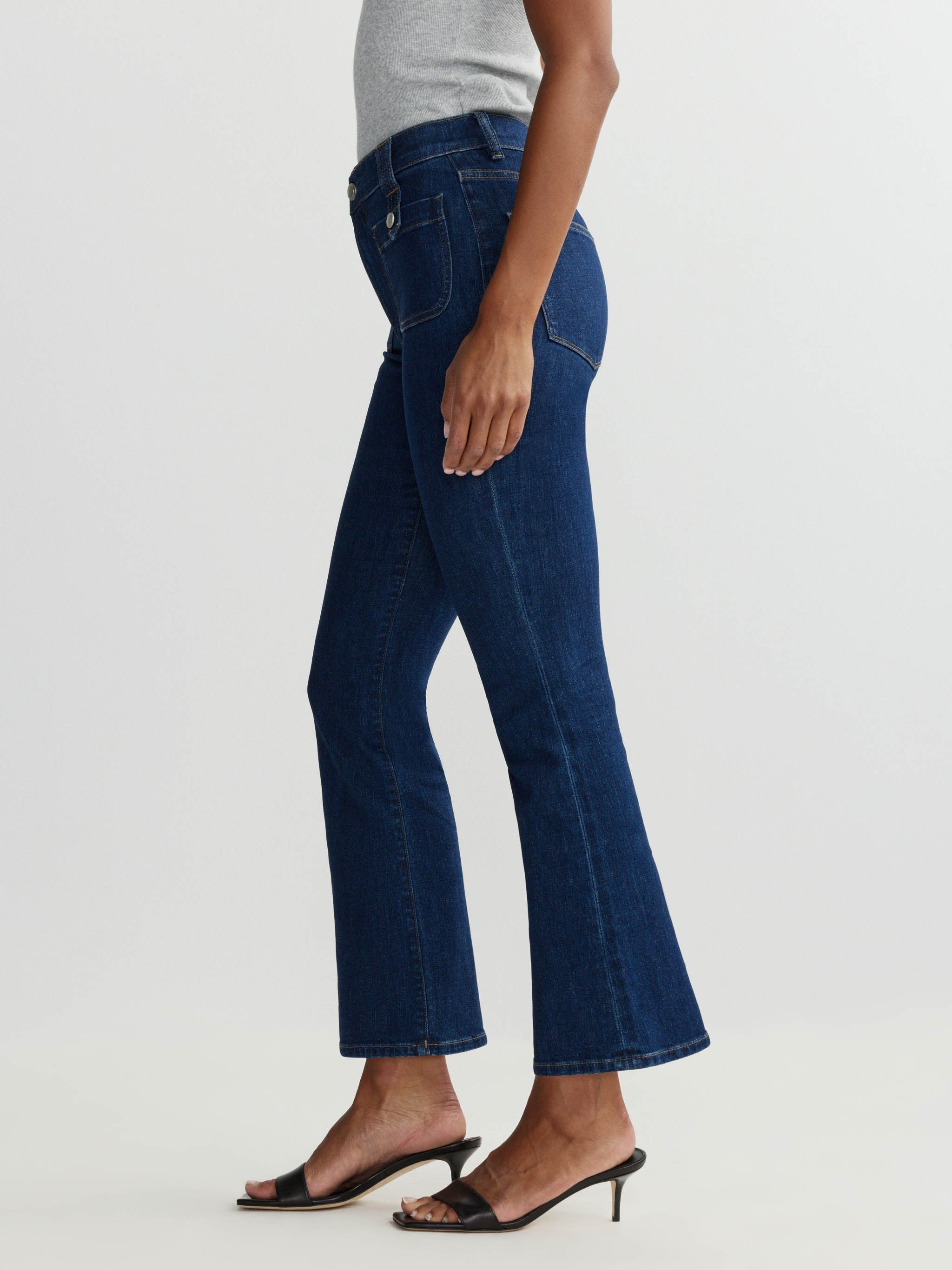 Person wearing dark blue jeans on a plain background