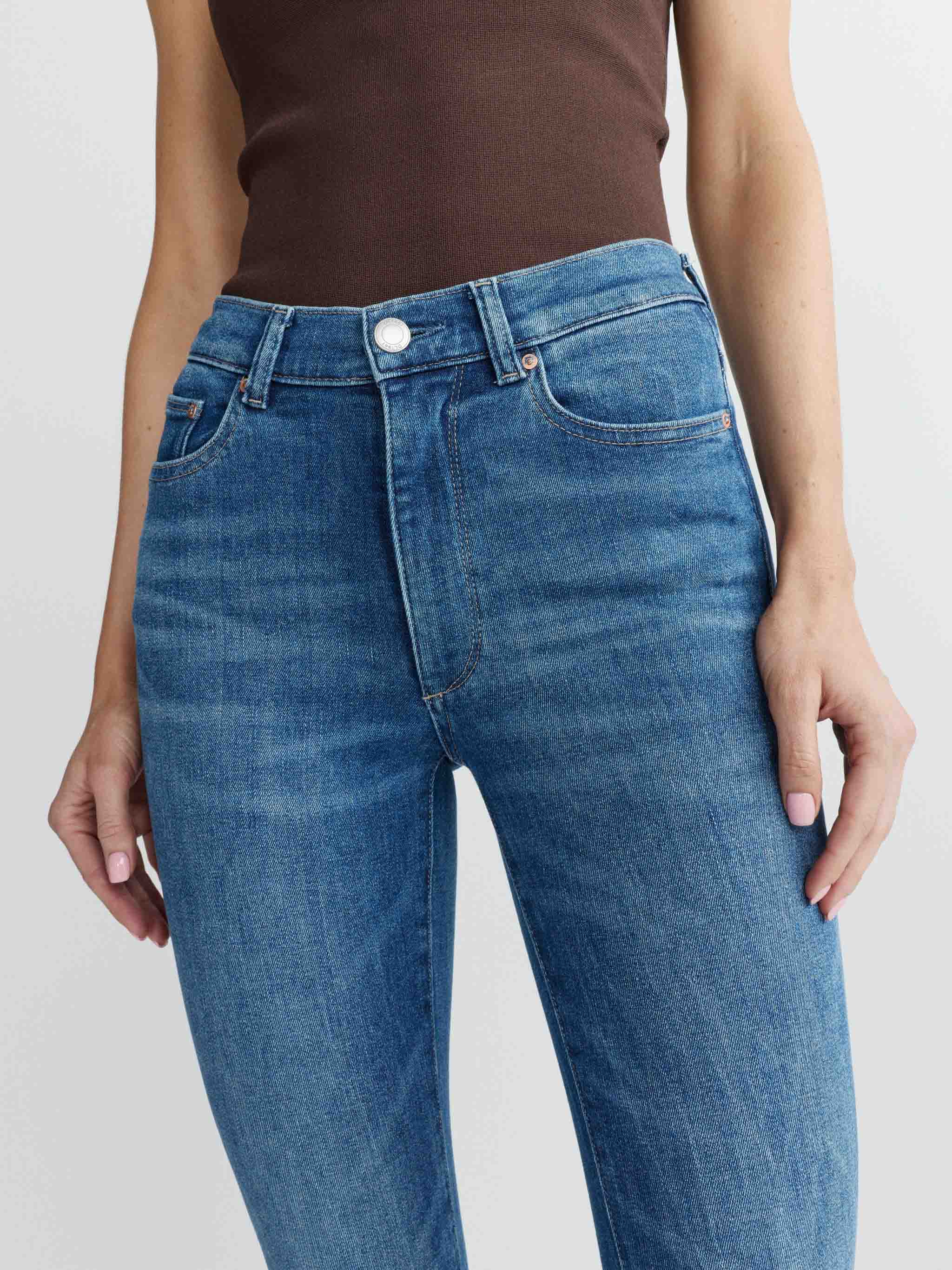 Blue jeans worn by a person on a plain background