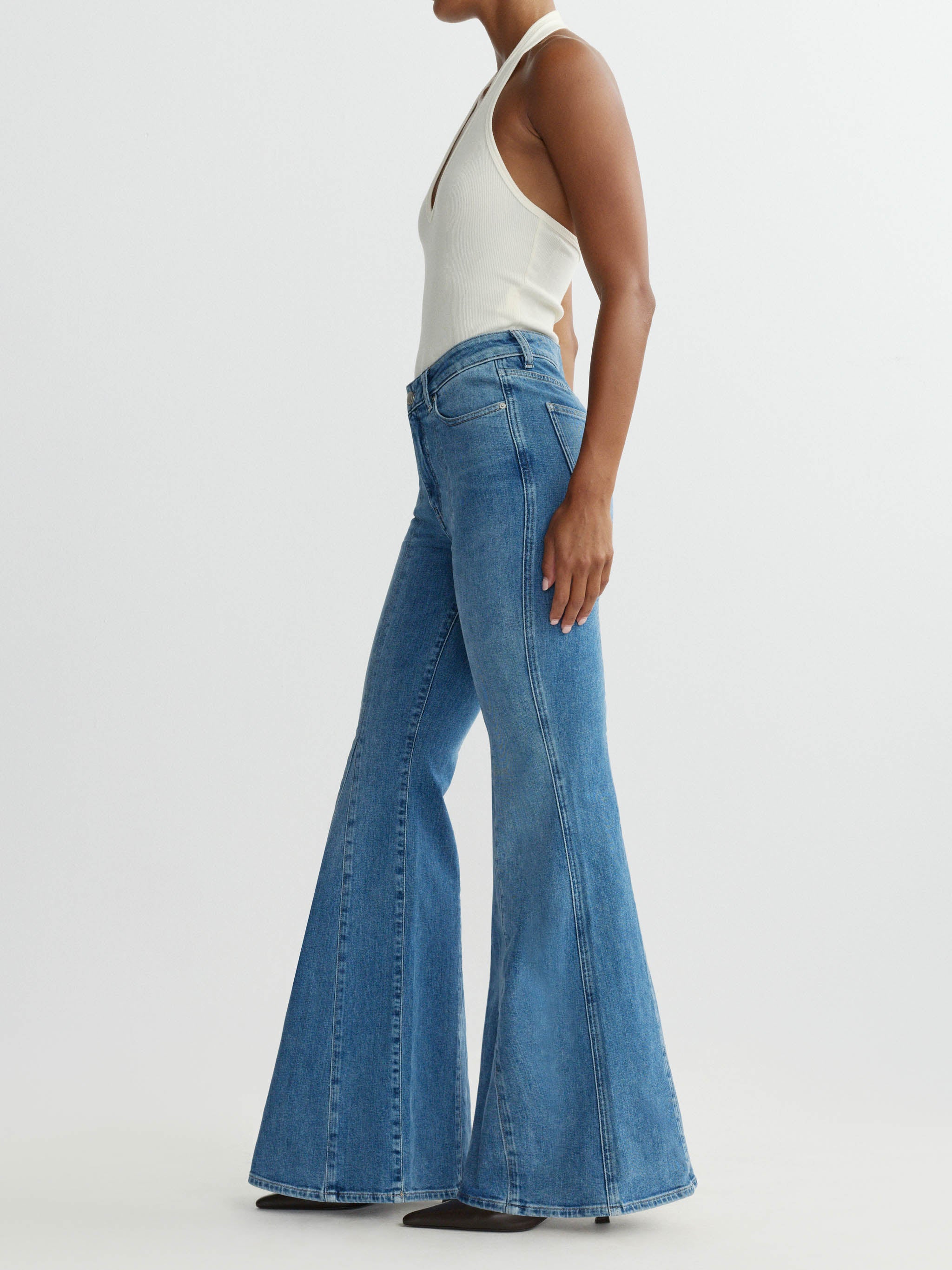 Person wearing blue flared jeans on a white background