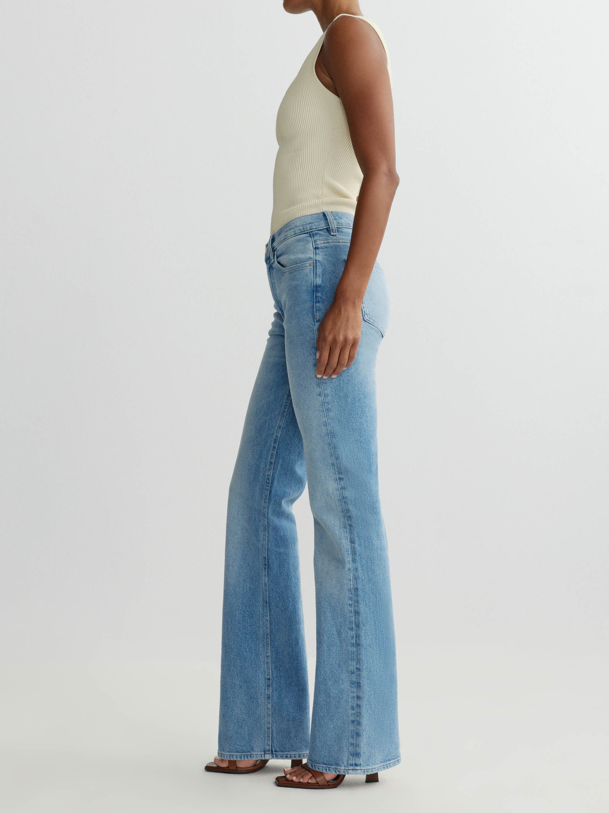 Person wearing light blue flared jeans on a white background