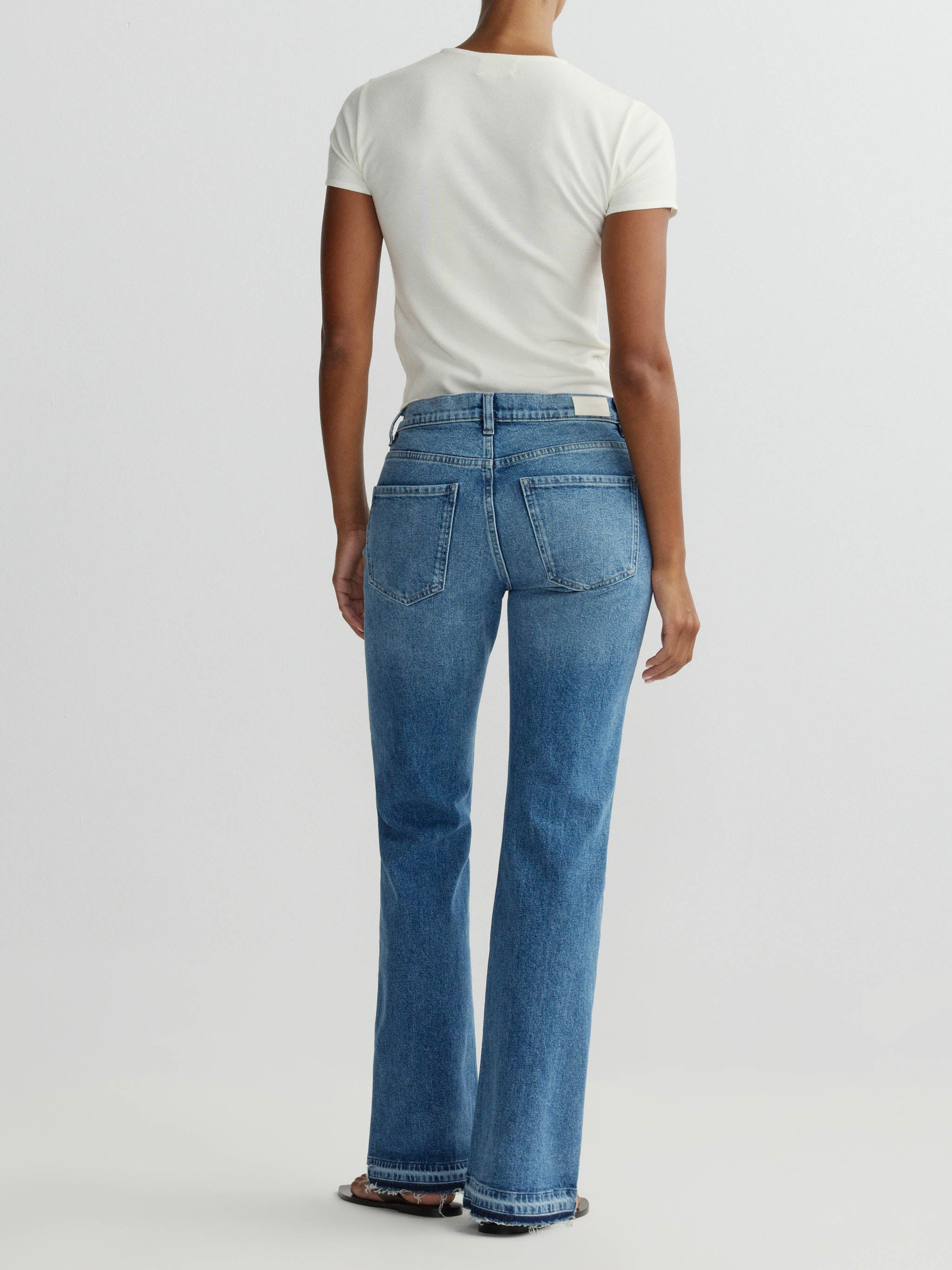 Person wearing blue jeans and a white t-shirt on a plain background