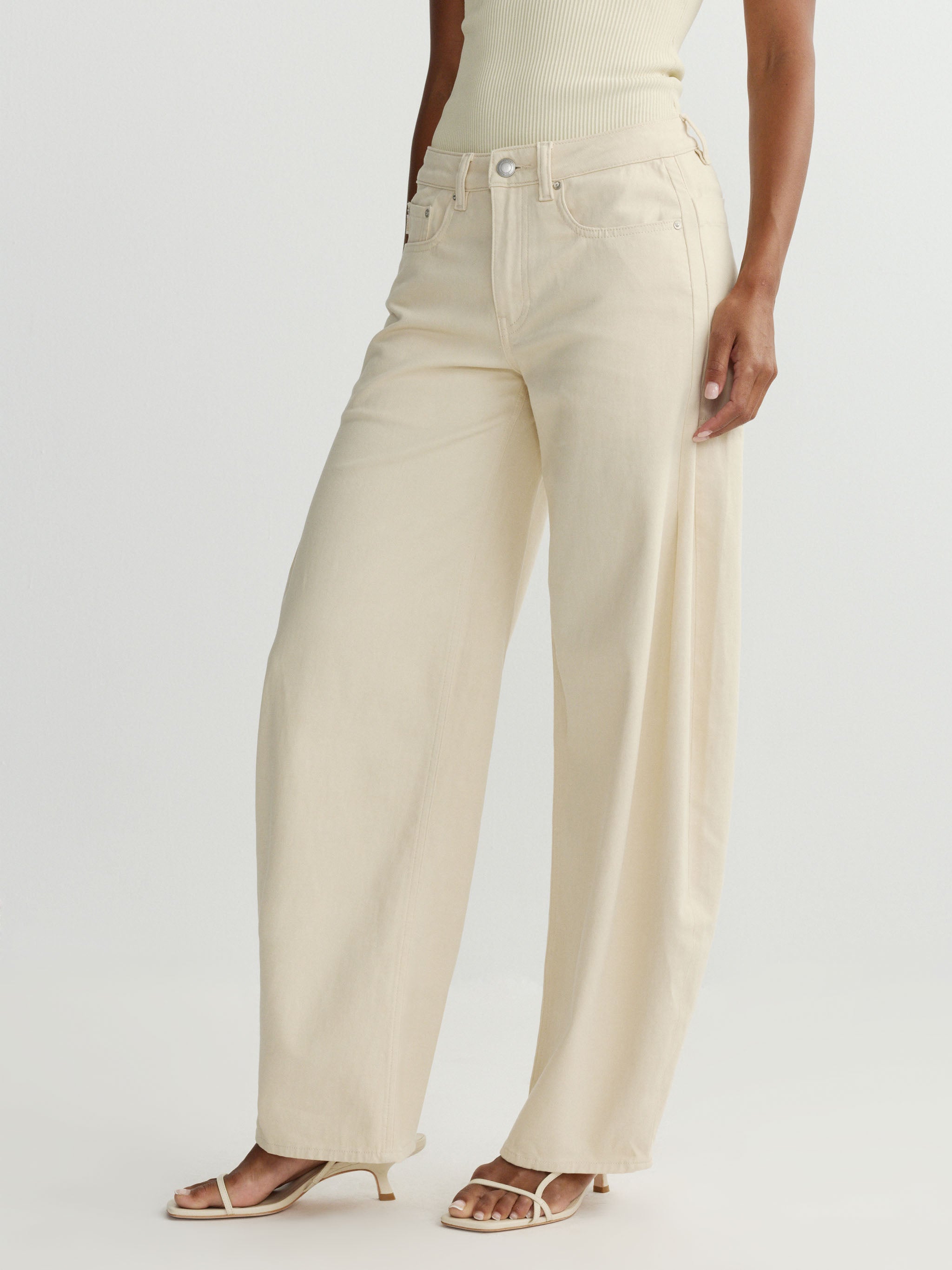 Person wearing beige wide-leg jeans on a plain background