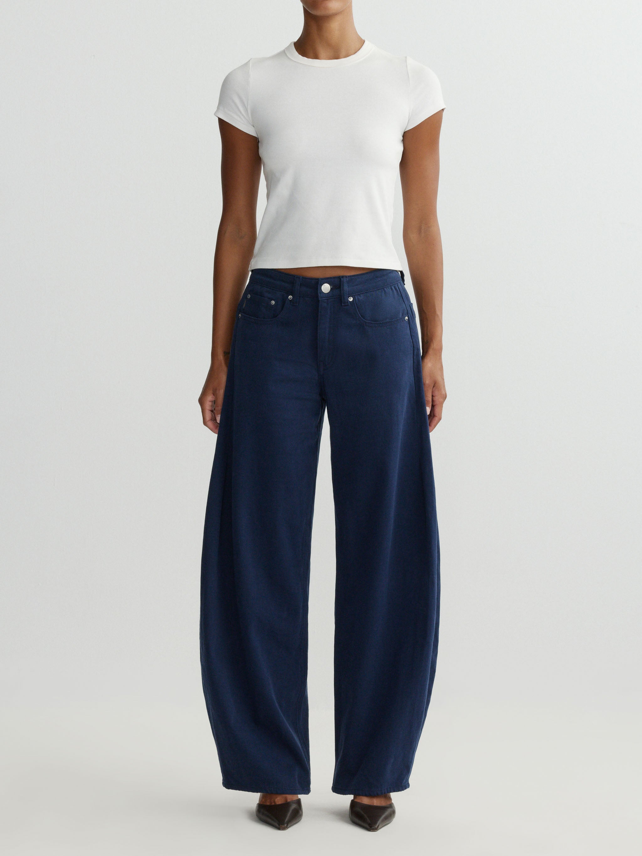 Person wearing navy wide-leg jeans and a white top on a light gray background