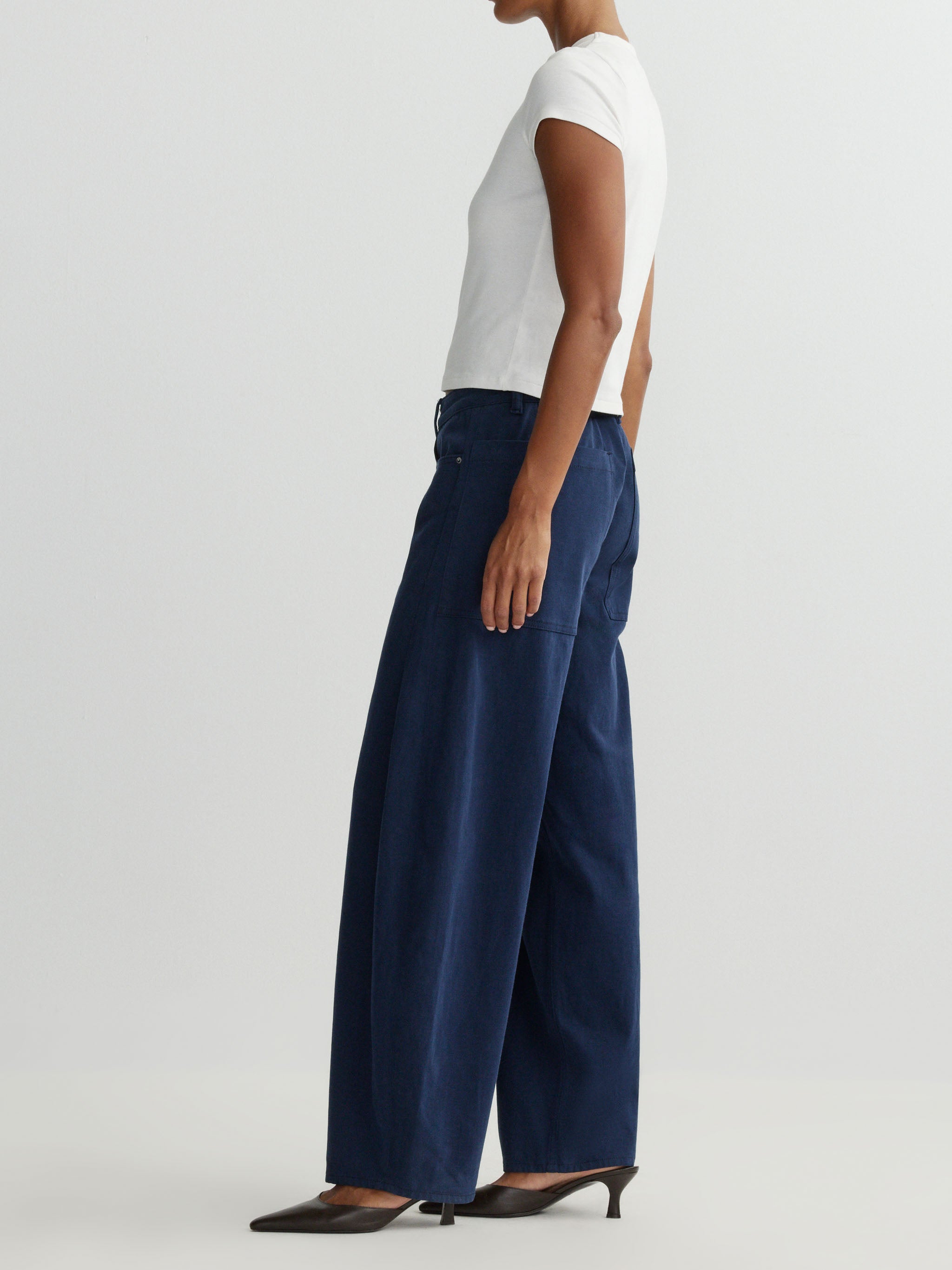Person wearing navy wide-leg pants and a white top on a light gray background