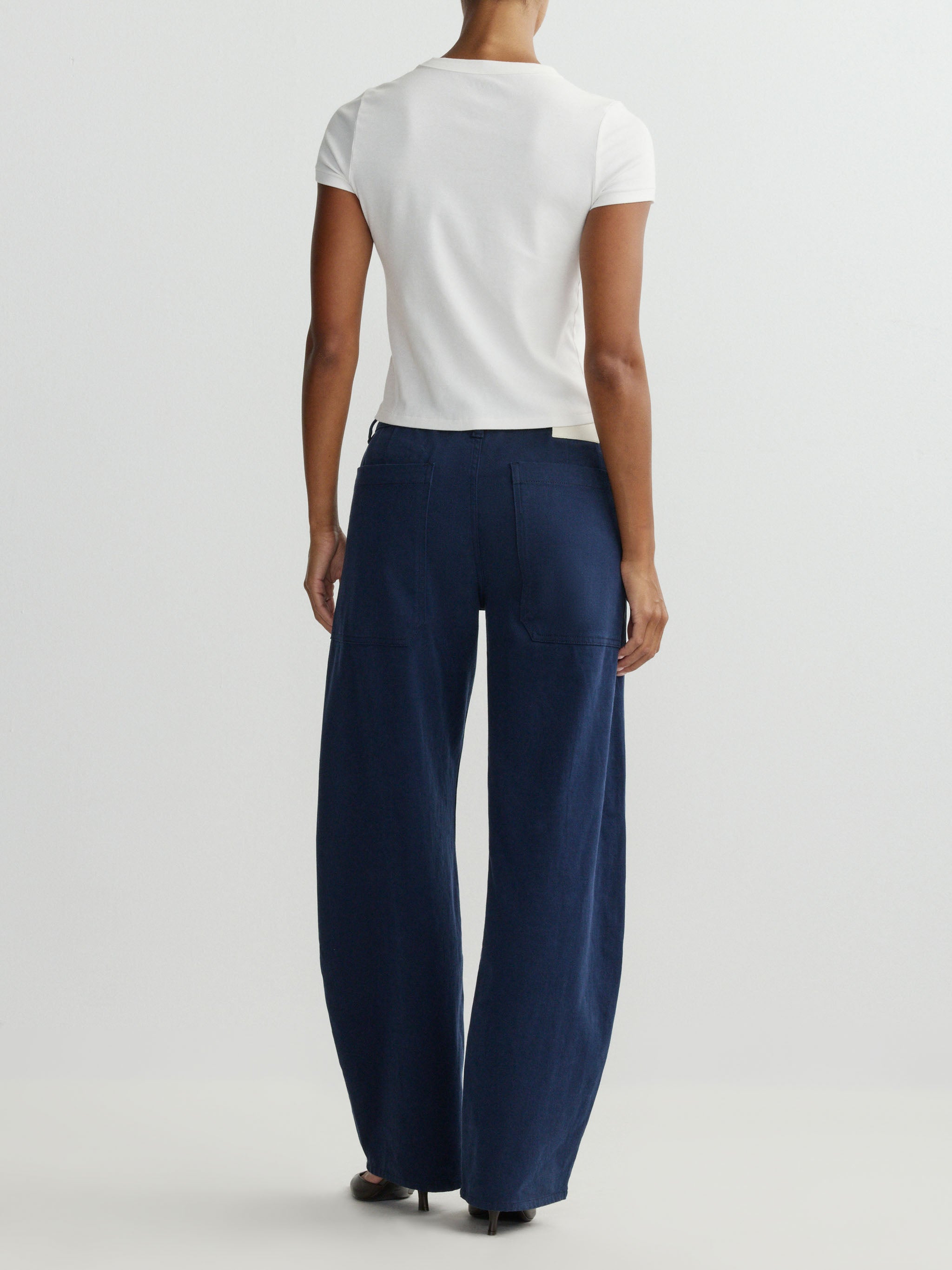 Person wearing a white top and navy pants on a light gray background