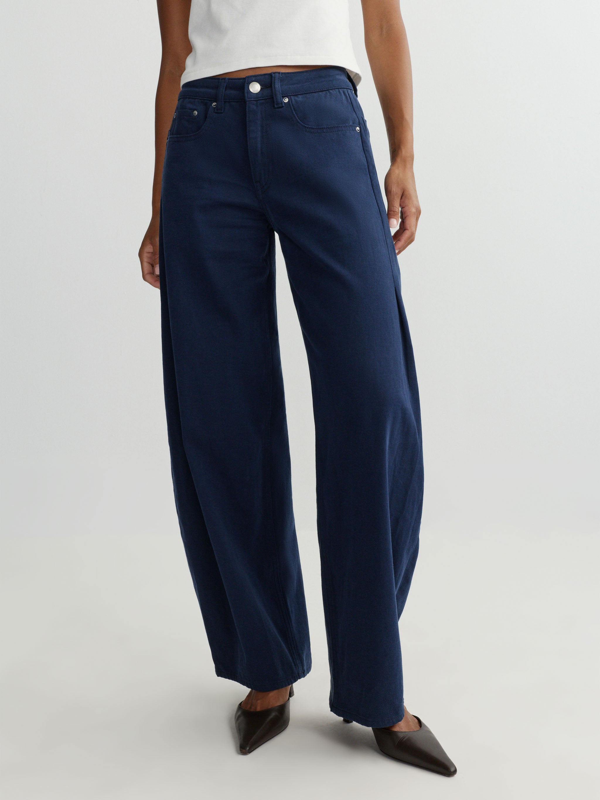 Navy blue wide-leg jeans worn by a person on a light gray background