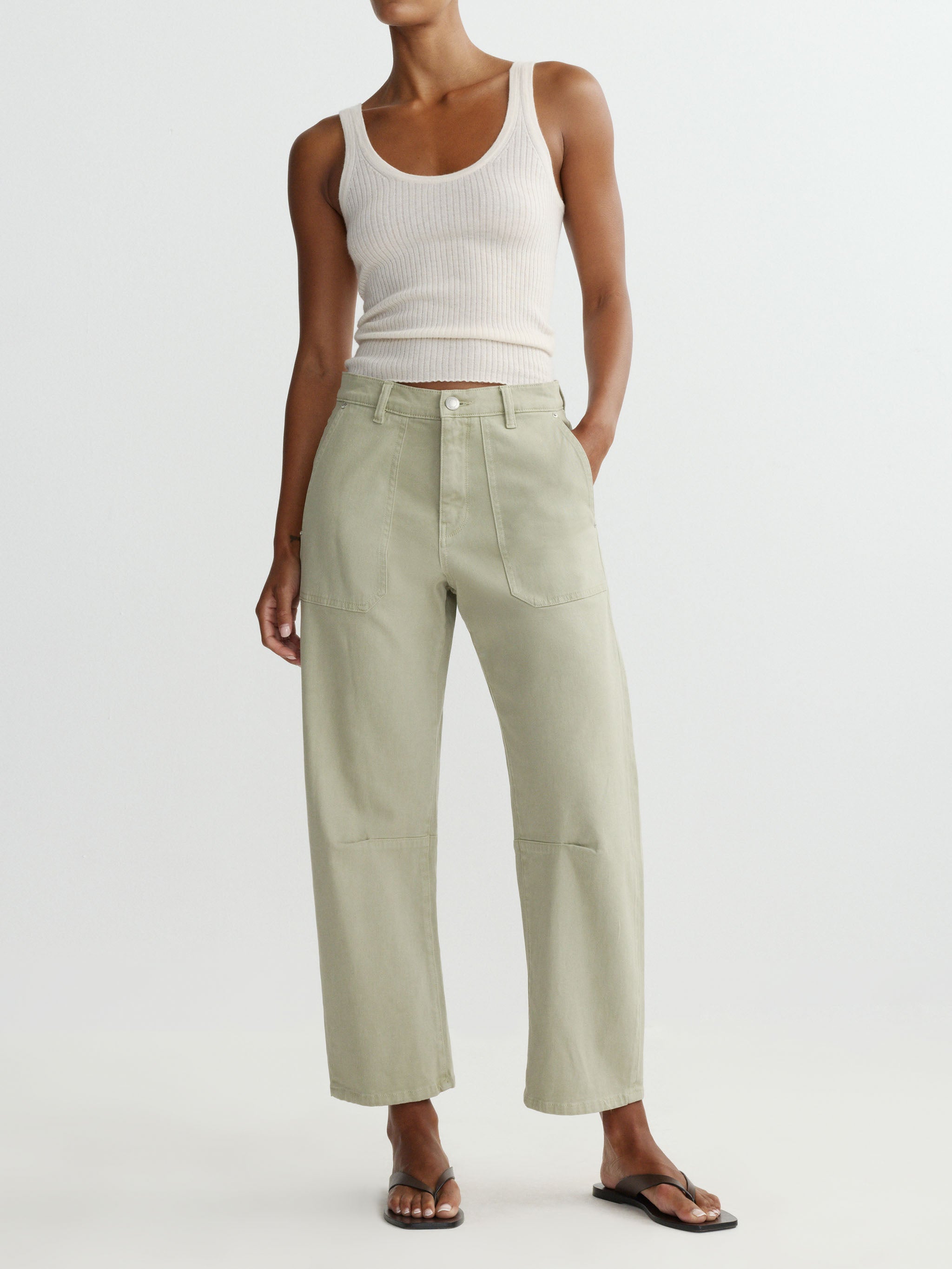 Person wearing a white tank top and light green pants on a white background