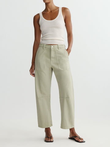 Person wearing a white tank top and light green pants on a white background