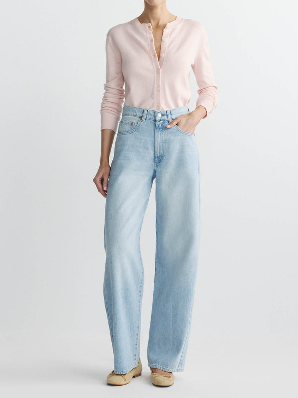 Person wearing light blue jeans and a pink shirt on a white background