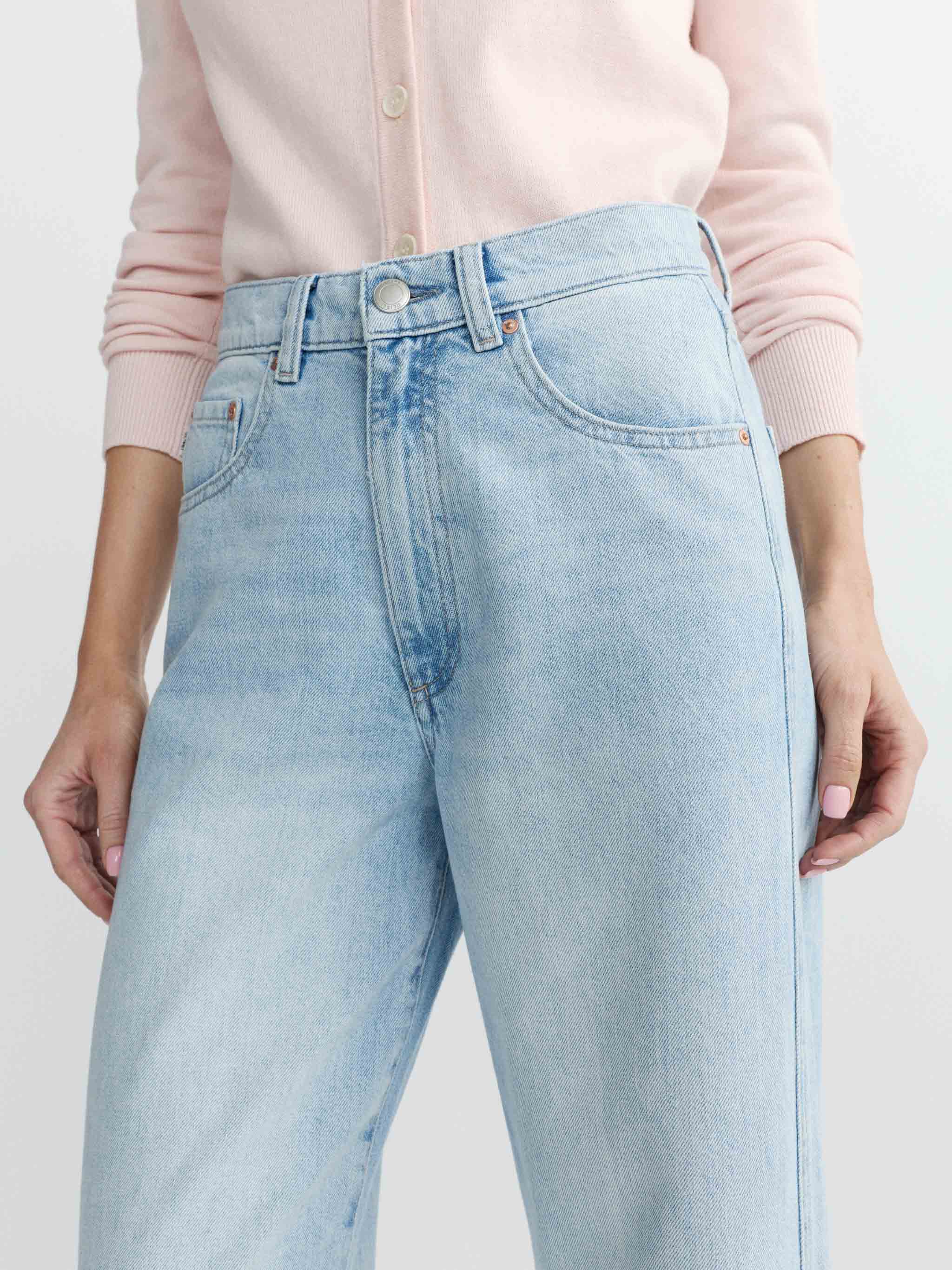 Light blue jeans worn by a person with a pink shirt on a white background