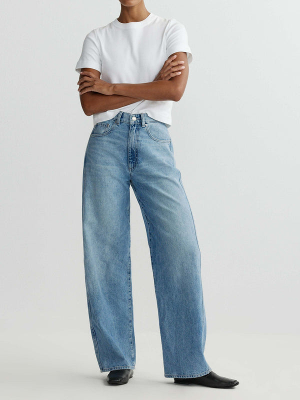 Person wearing light blue jeans and a white t-shirt on a plain background