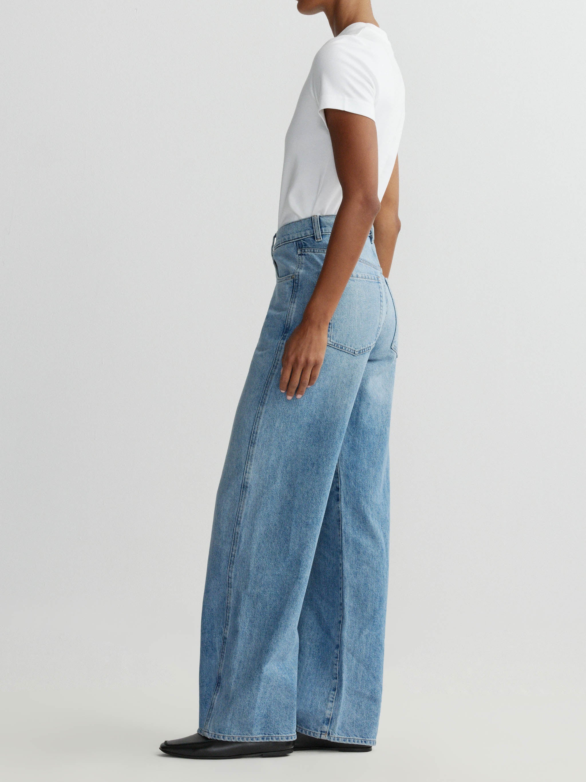 Person wearing light blue wide-leg jeans on a plain background
