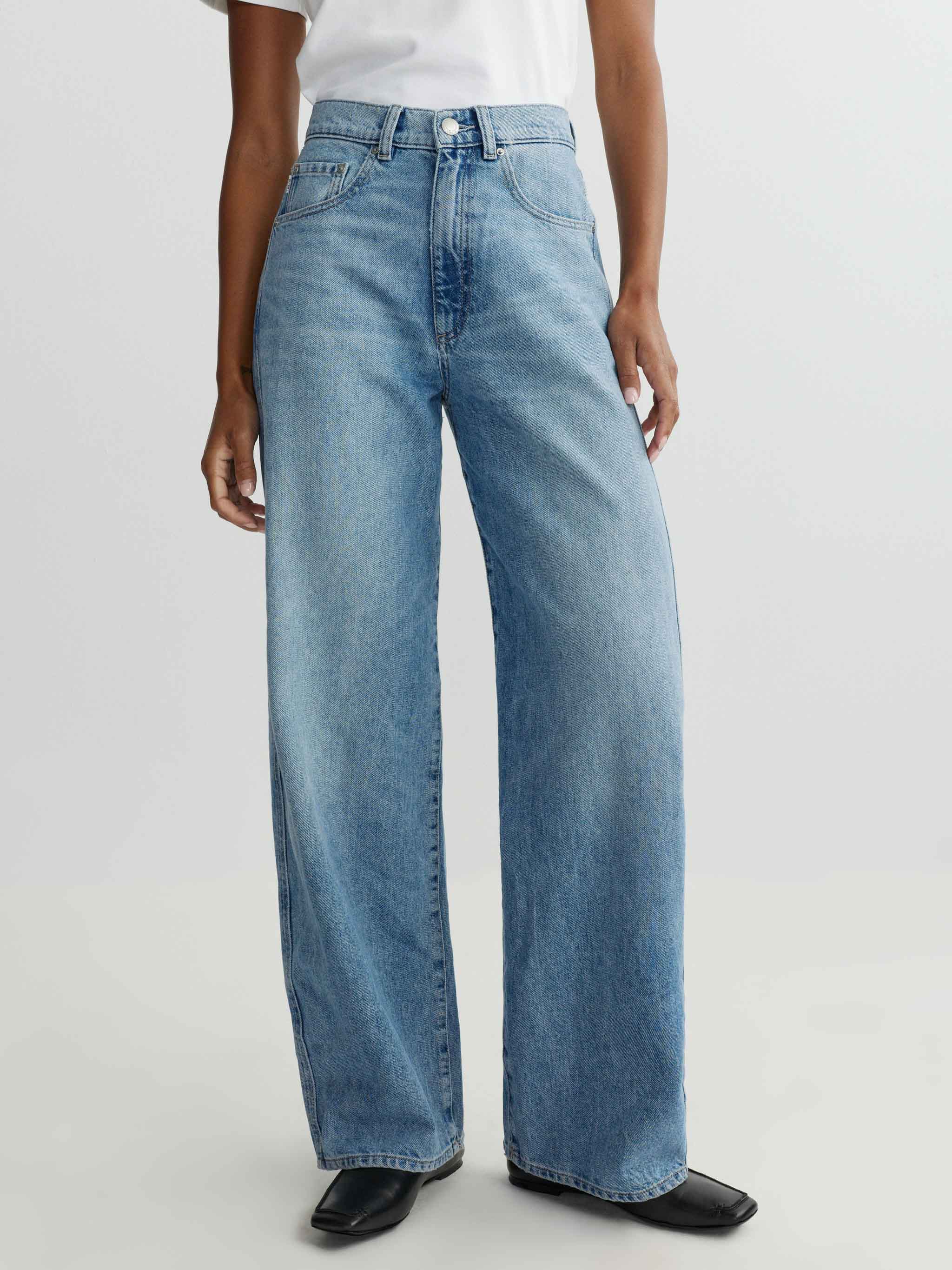 Person wearing light blue jeans on a white background